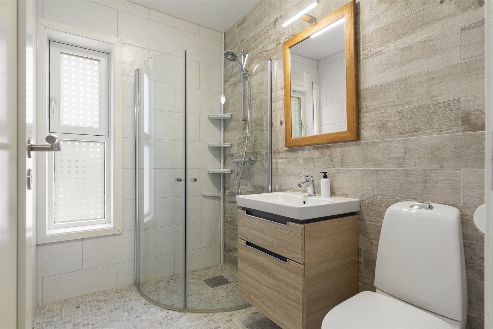 Baderommet er utstyrt med toalett, baderomsinnredning og dusjhjørne. Galleribilde