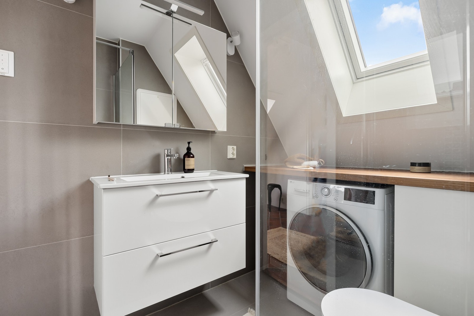 Dusjhjørnet med glassdører sammen med de flotte flisene er med på å skape et moderne preg på baderommet. Galleribilde