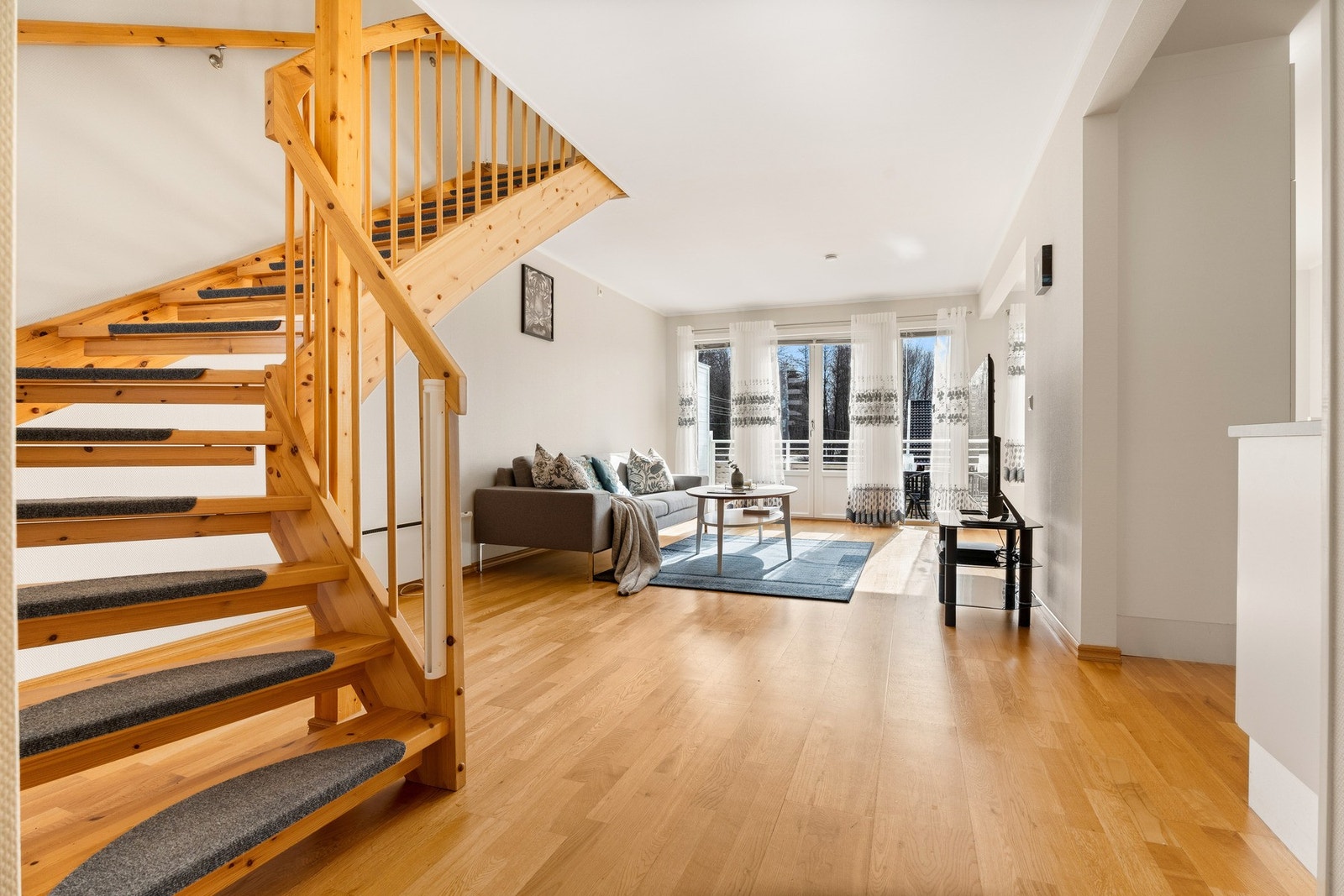 Lys og romslig stue med store vinduer som slipper inn mye naturlig lys. Galleribilde