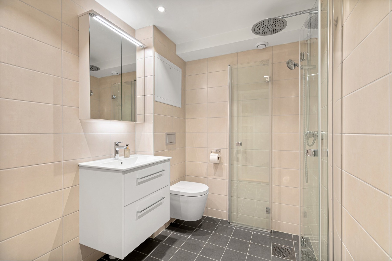 Nytt og tidsmessig flislagt dusjbad/w.c. med vegghengt toalett, innebygget vask og speilhylle med lys. Galleribilde