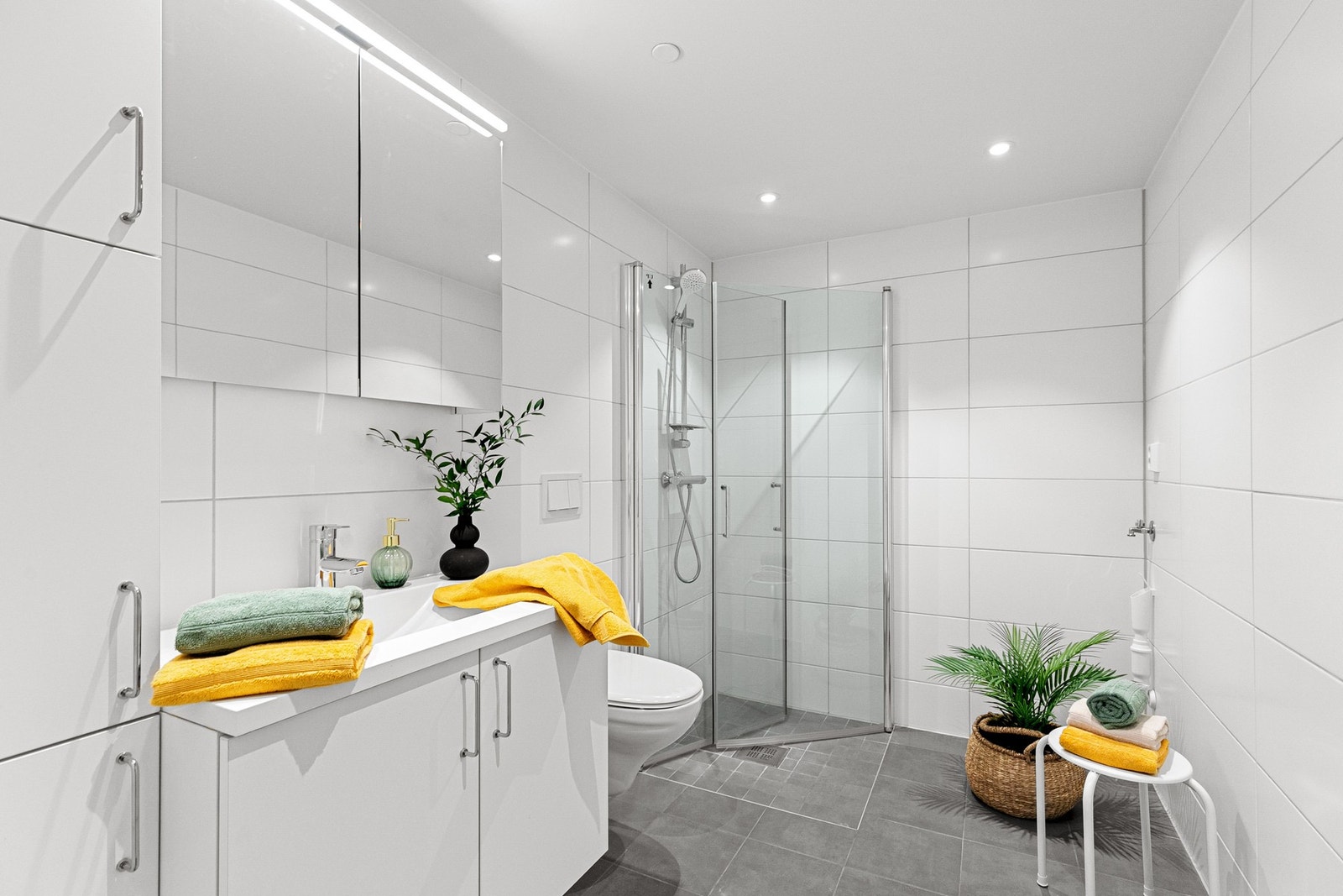 Lekkert, flislagt bad med opplegg for vaskemaskin og pen innredning Galleribilde