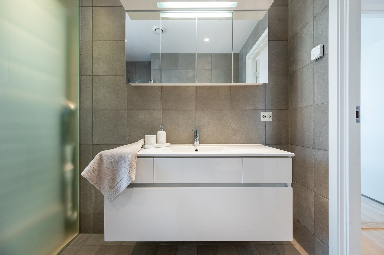 Rommet er innredet med servantinnredning, speilskap med lys, stort dusjhjørne, toalett og opplegg for vaskemaskin. Galleribilde