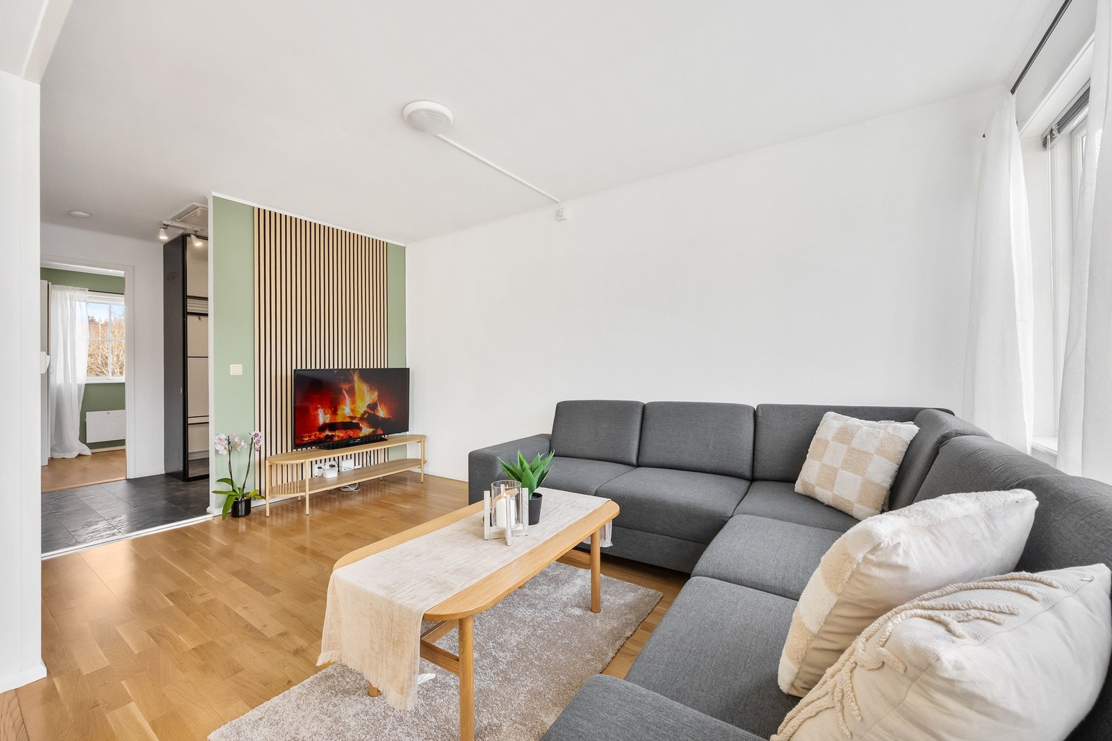 Den innbydende stuen har store vindusflater som slipper inn rikelig med naturlig lys og skaper en luftig og behagelig atmosfære Galleribilde