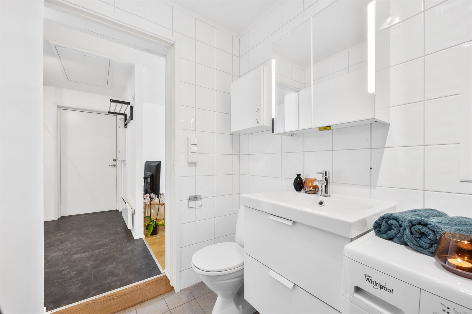 Innredningen består av en servant, speilskap med belysning og overskap for praktisk oppbevaring. Videre har badet et frittstående toalett og et dusjkabinett. Det er opplegg for vaskemaskin Galleribilde