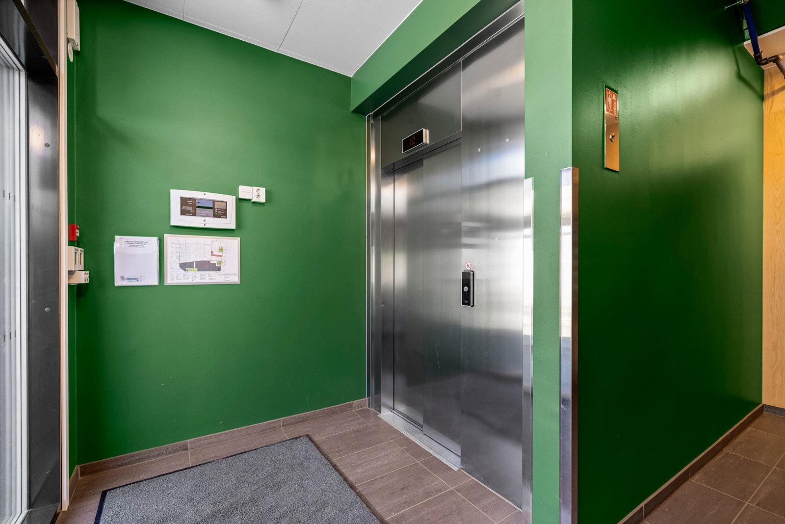 Innbydende inngangsparti med heisadkomst til boligetasjen. Leiligheten ligger en etasje over bakkeplan og vender inn mot indre gårdsrom. Galleribilde