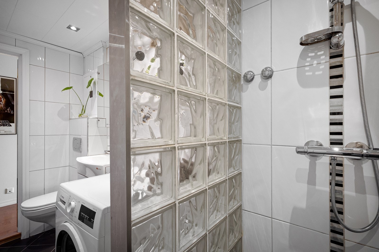 Helfliset bad som er utstyrt med vegghengt toalett, dusjhjørne og baderomsmøbler. Galleribilde