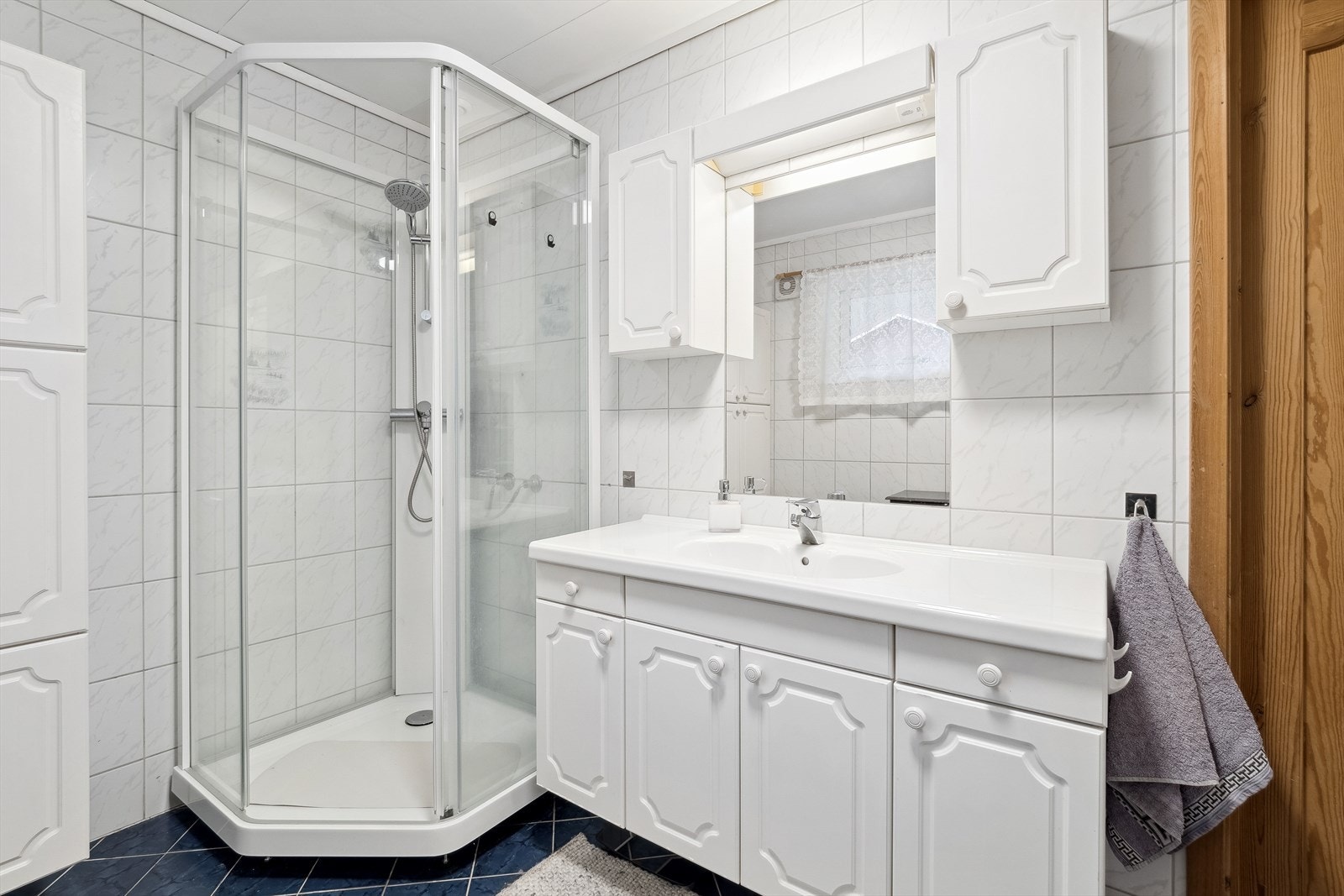 Badet har innredning med servant, overskap, speil og belysning, høyskap, toalett og dusjkabinett. Galleribilde