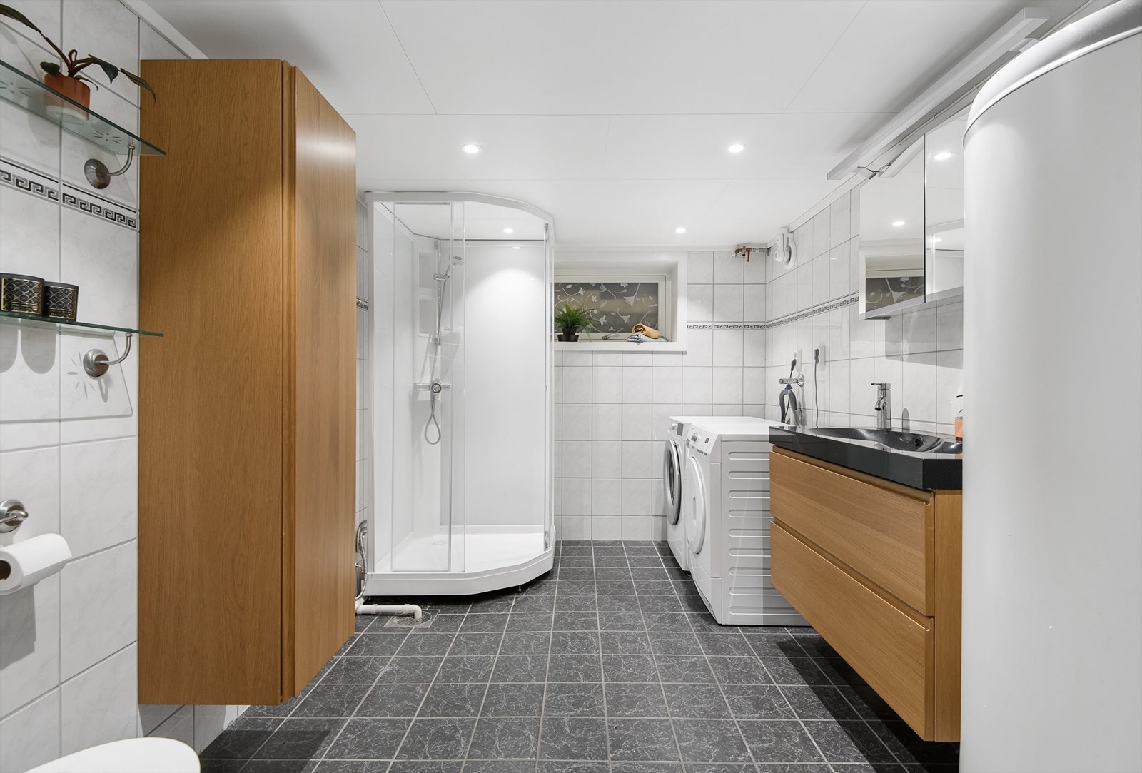 Lyst, flislagt baderom i kjelleretasjen med opplegg for vaskemaskin Galleribilde