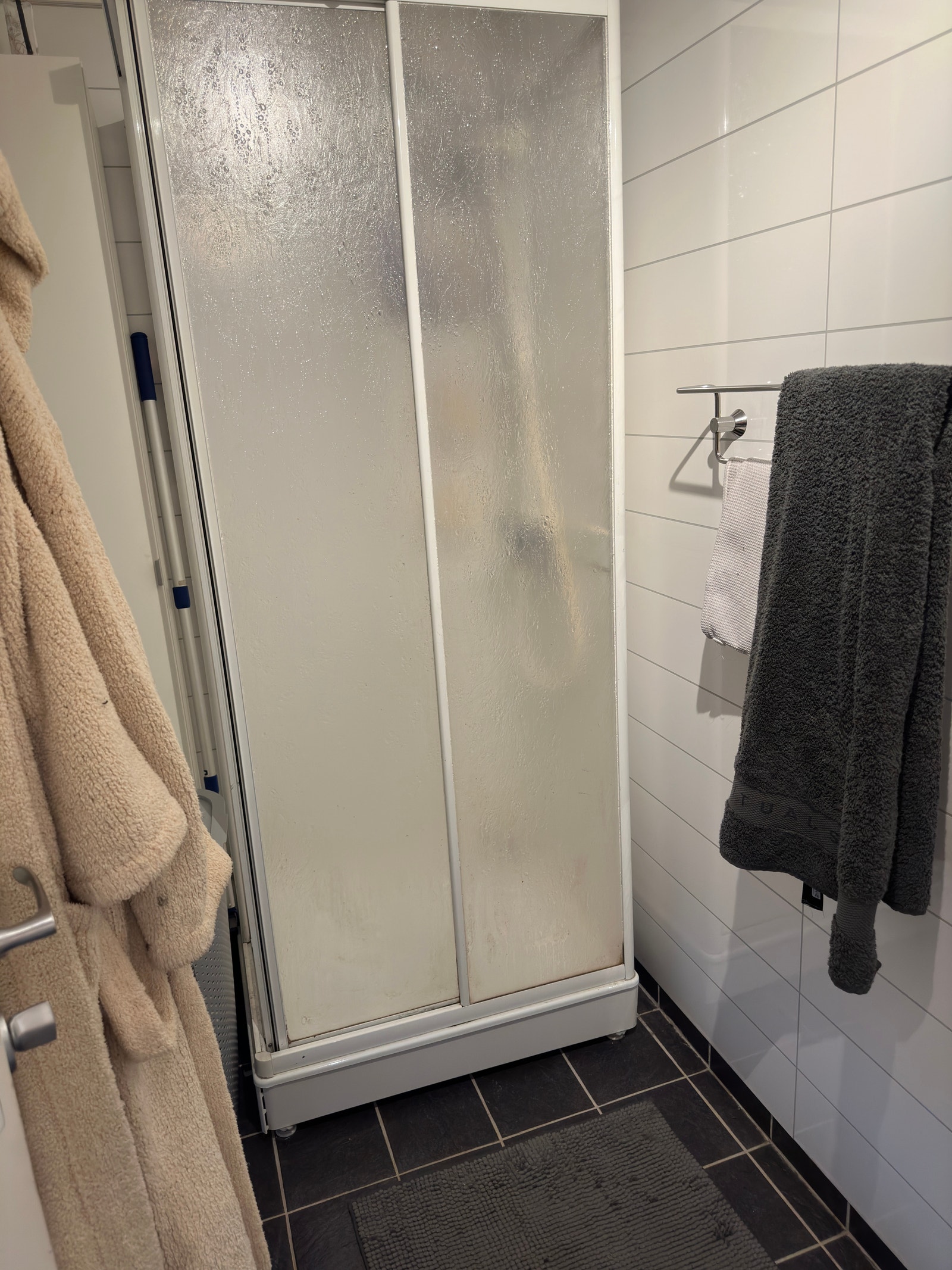 Flislagt bad med dusjkabinett, servant med speilskap og toalett. Galleribilde