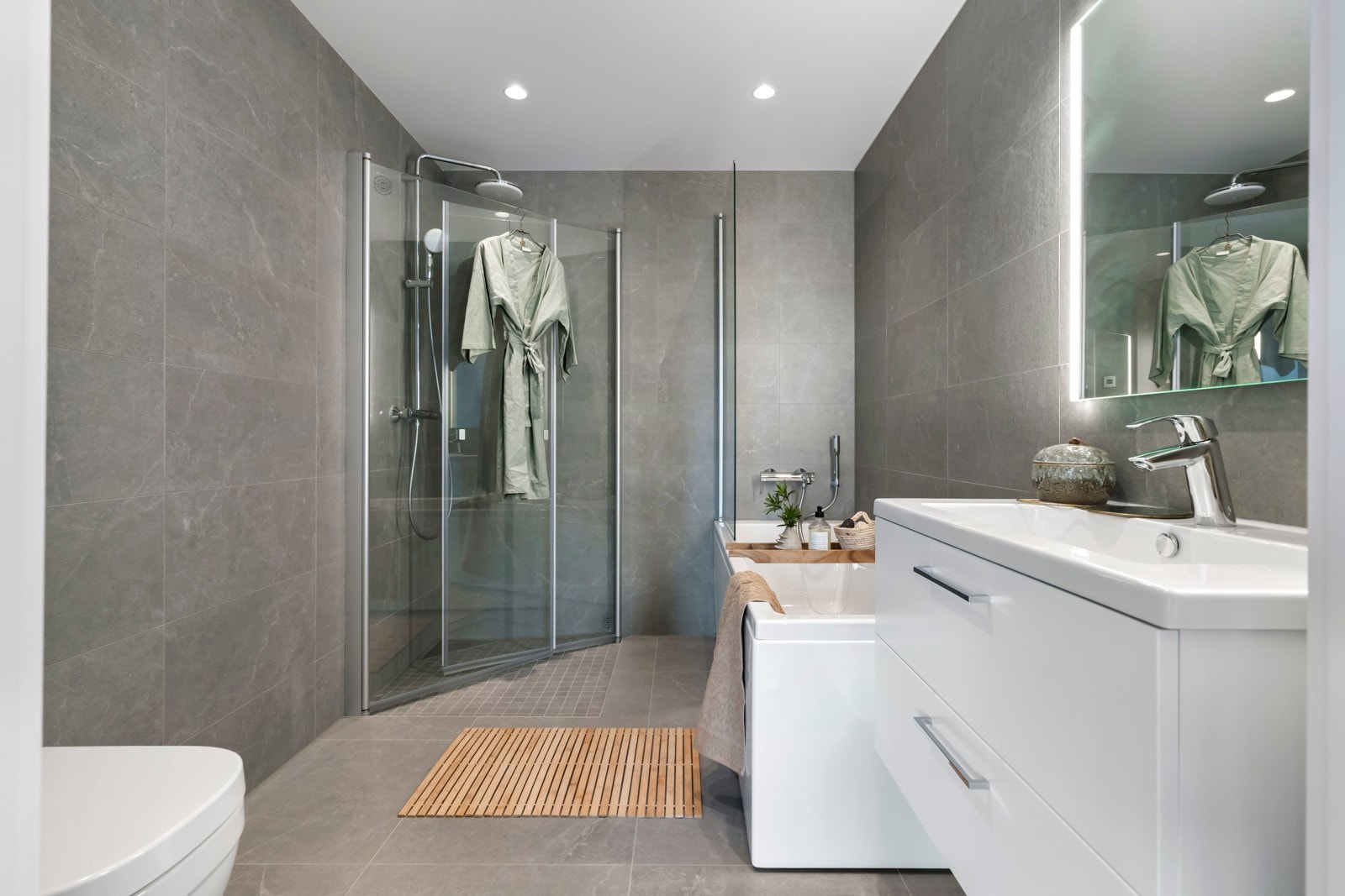 Badet er meget innbydende og tidsriktig innredet med grå fliser på vegger og på gulv med gulvvarme, samt behagelig downlights i himling. Galleribilde