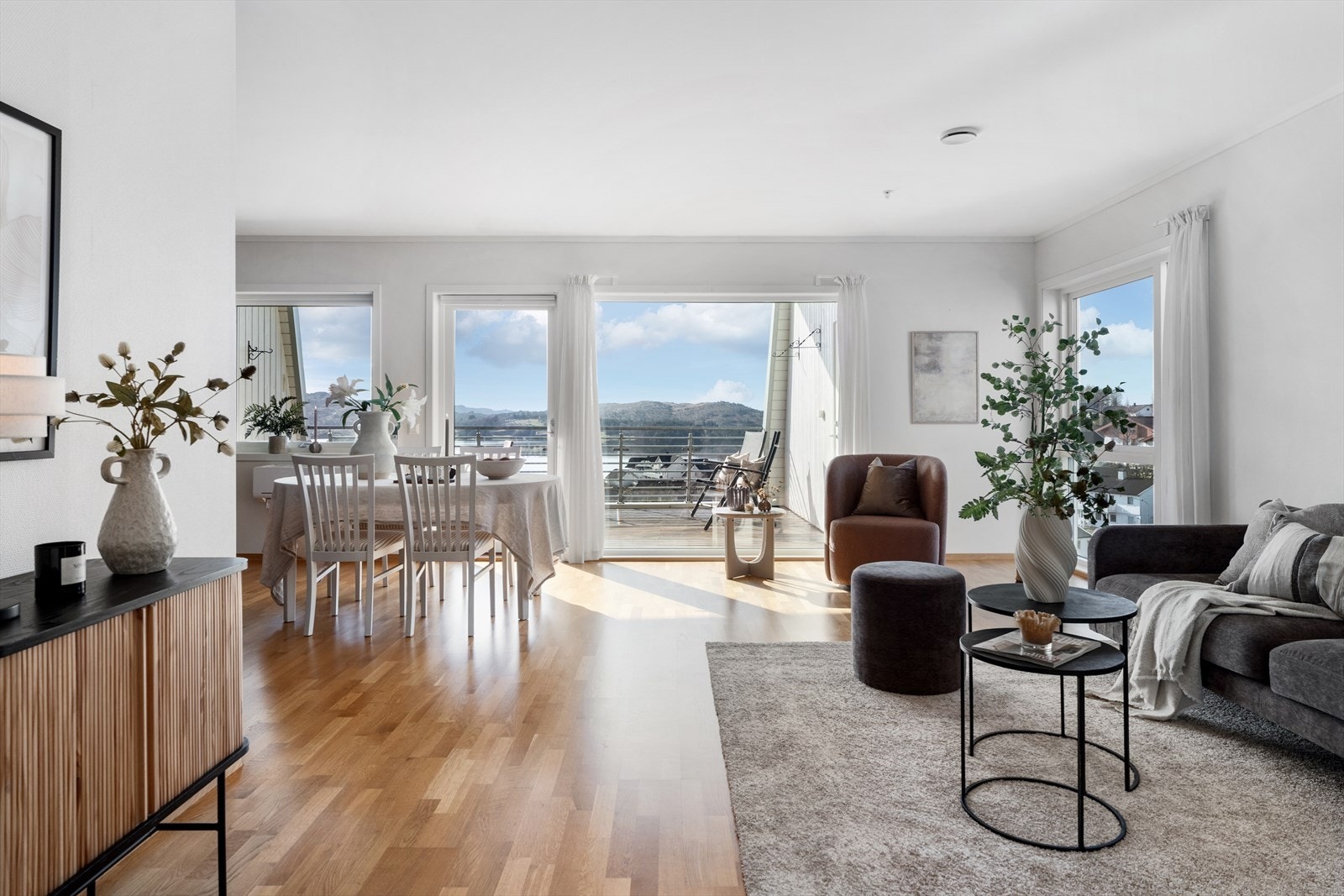 Leiligheten har en lys og luftig stue/kjøkkenløsning med plass til både sofagruppe og spisebord Galleribilde