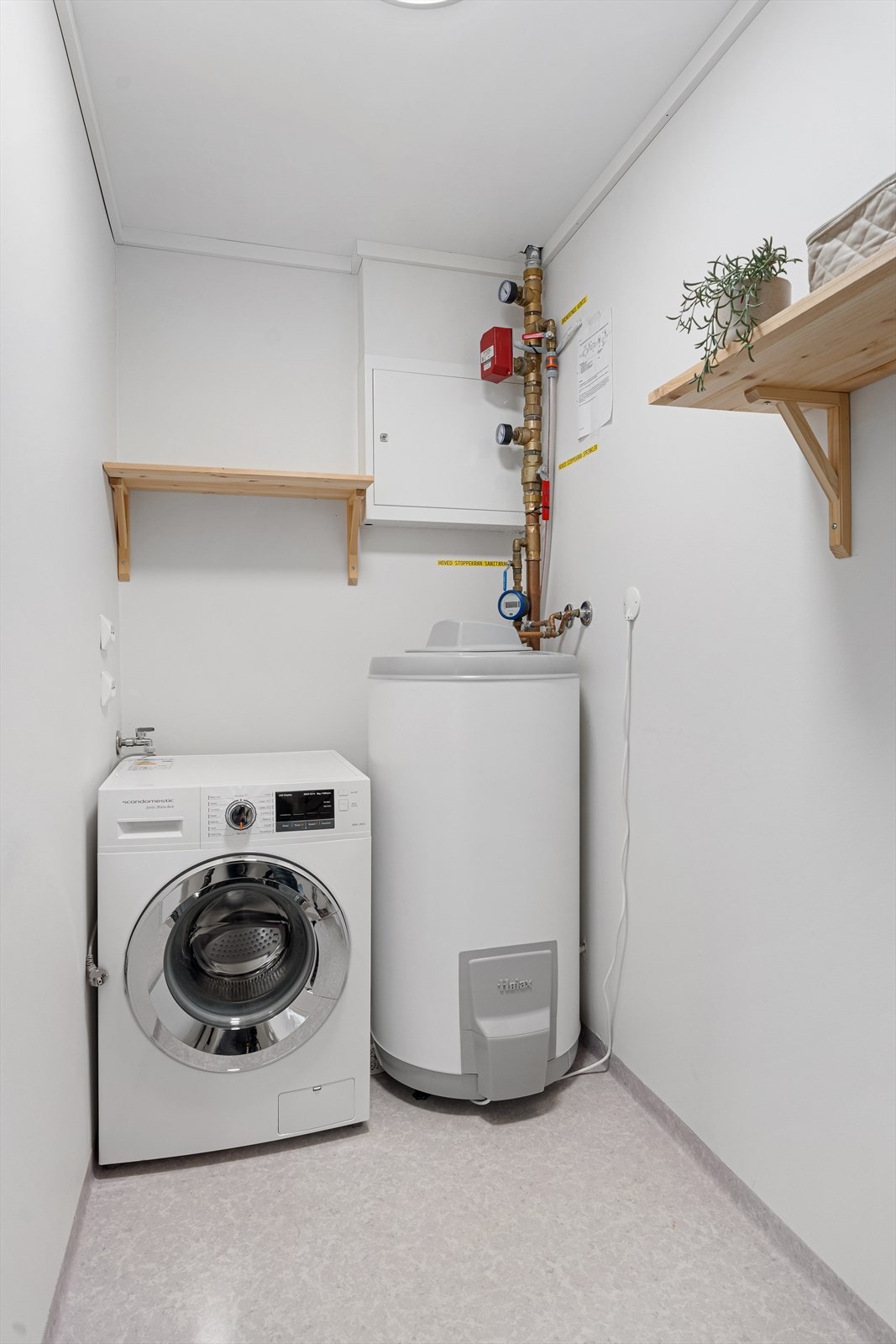 Fra badet er det direkte adkomst til praktisk vaskerom med belegg på gulv og malte plater på veggene Galleribilde