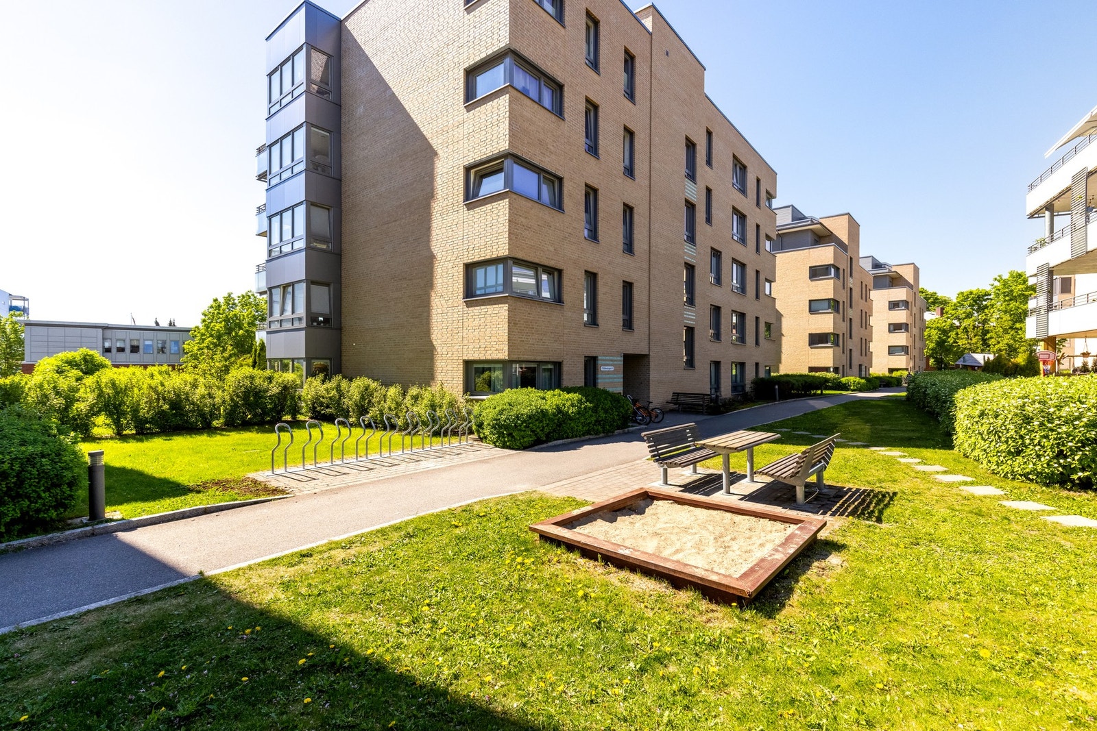 En idyllisk og rolig bakgård med plen, beplantning og lekeapparater for barna. Galleribilde
