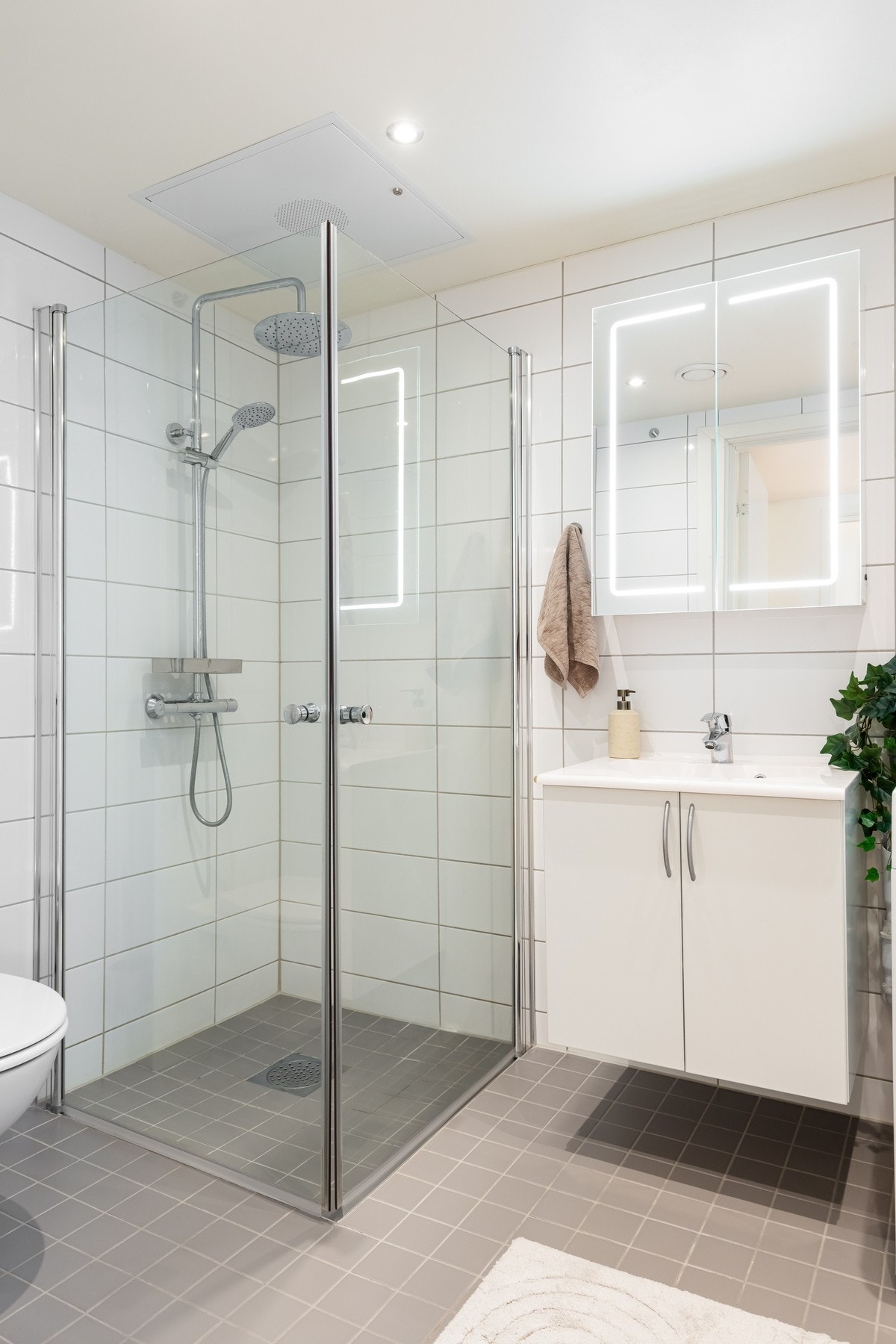 Videre er det dusjhjørne med innfellbare glassdører som frigjør plass på gulvet og vegghengt toalett. Badet har opplegg for vaskemaskin og plass til tørketrommel. Galleribilde