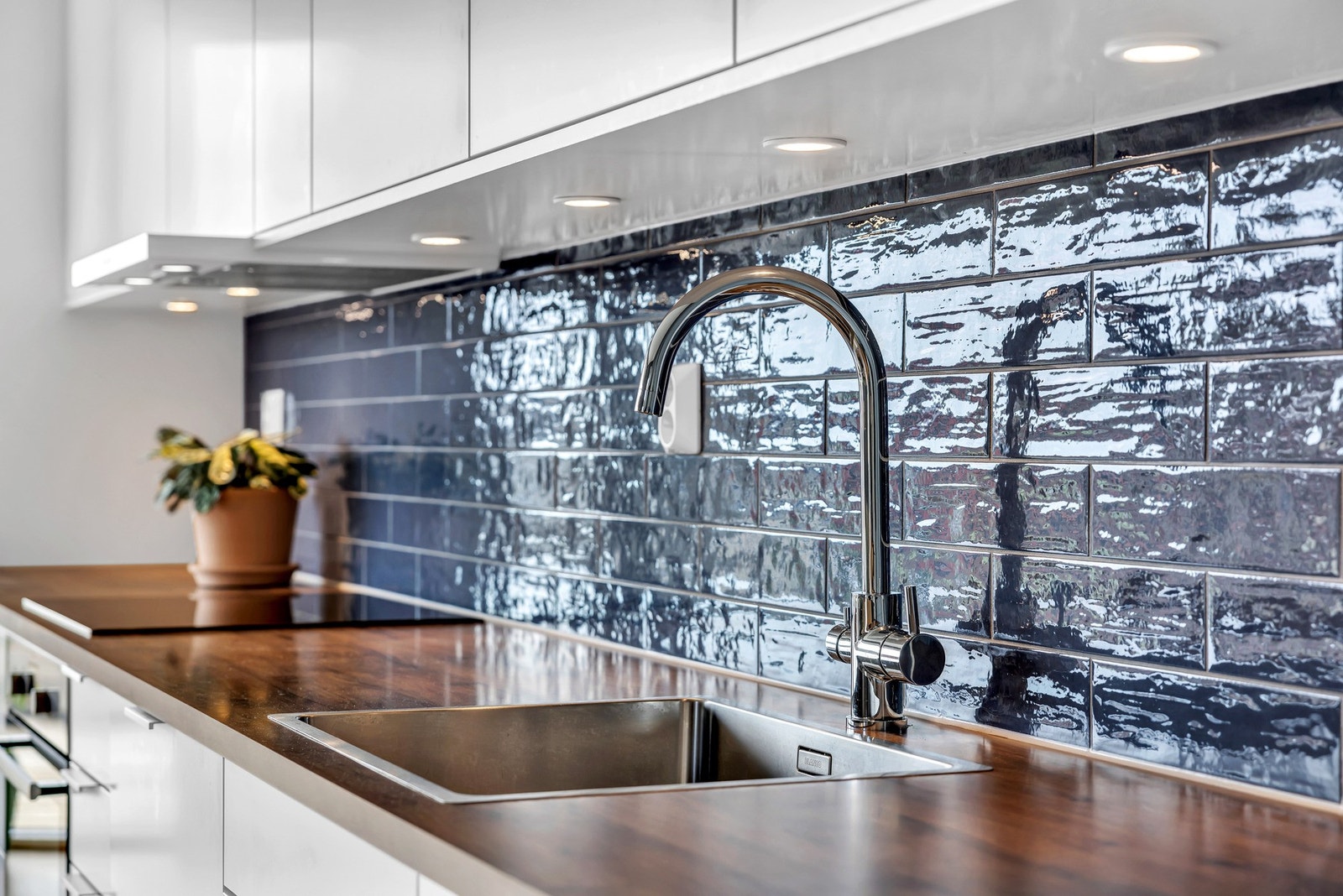 Nedsenket oppvaskkum med ett-greps armatur og flislagt med nydelige blå fliser mellom benkeplate og overskap. Galleribilde