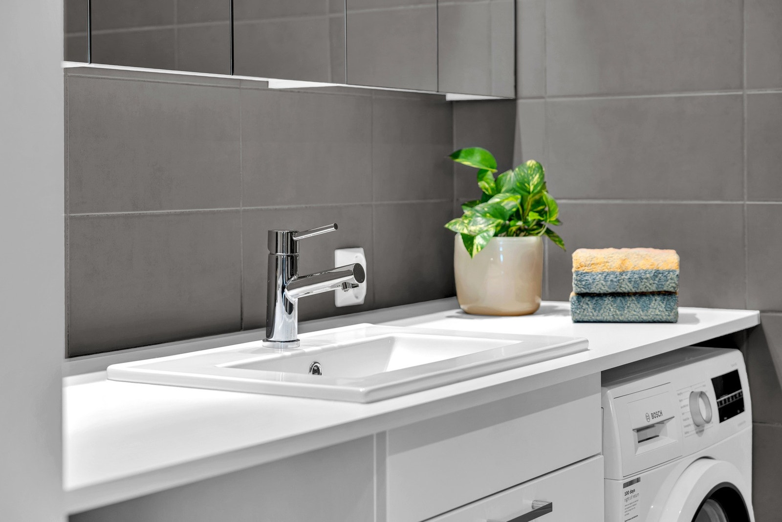 Tidløs hvit baderomsinnredning med servant, vegghengt speilskap og overbelysning. Galleribilde