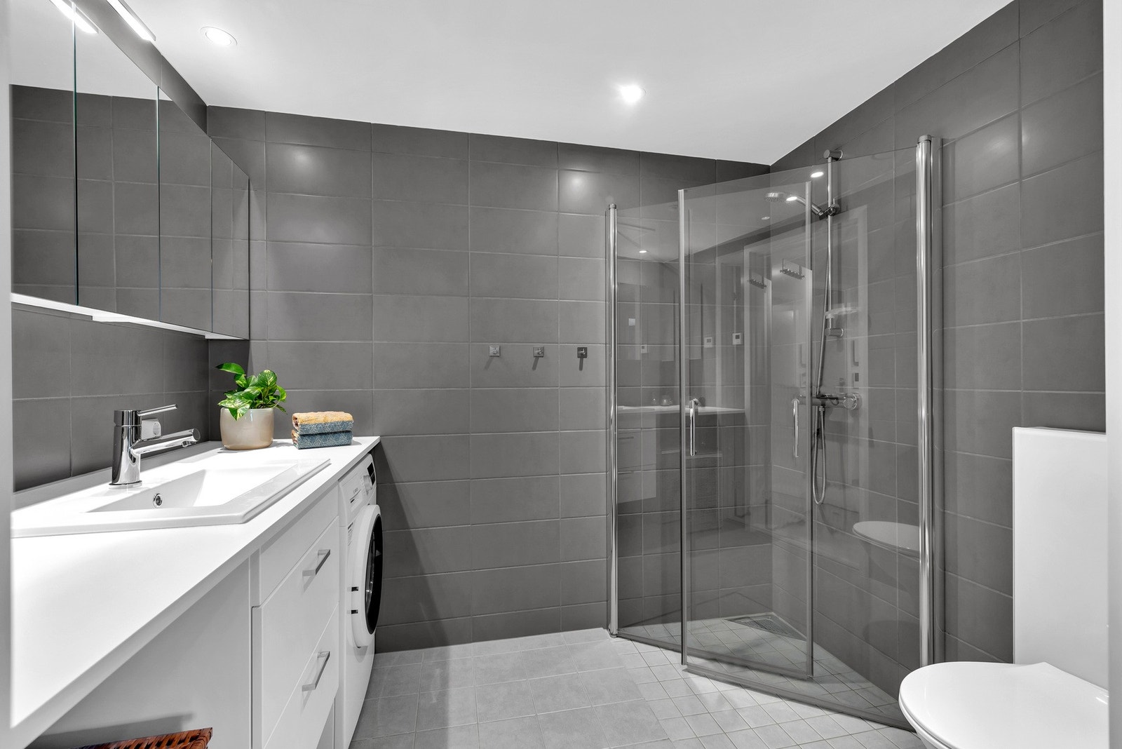 Baderommet fremstår delikat og er fra byggeåret 2021. Det er flislagt med mørke veggfliser og varme i gulv. Galleribilde