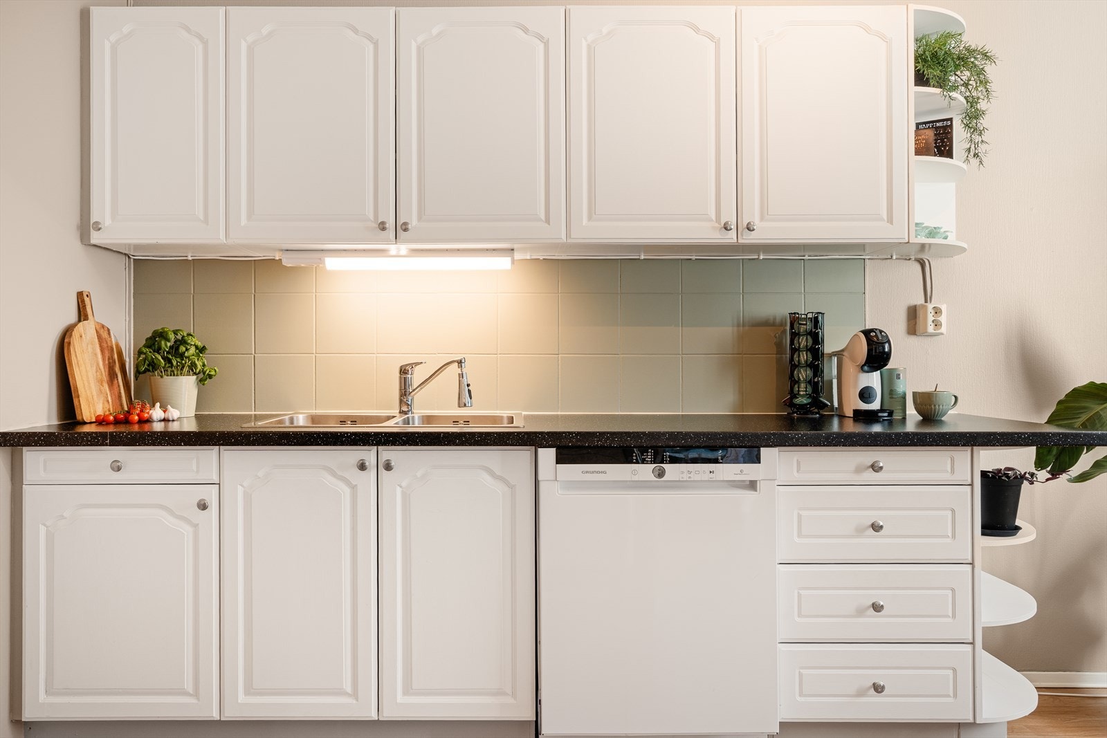 Kjøkkenet har en stilren innredning med profilerte fronter, laminat benkeplate, stål oppvaskkum og ventilator Galleribilde