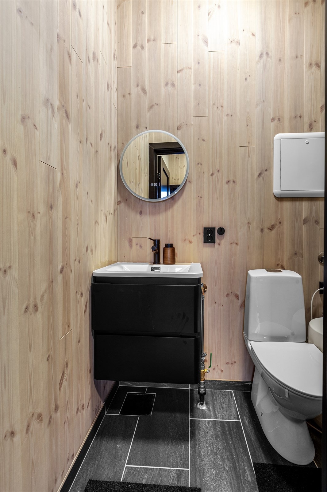 Pent toalettrom utstyrt med servant, WC, servantskap, bereder og rørskap. Galleribilde