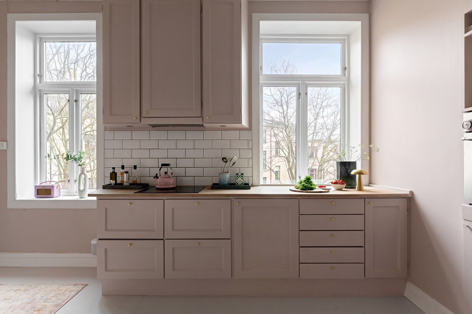 Kjøkkeninnredning med profilerte fronter, fliser på vegg over benkeskap og belysning under overskap Galleribilde