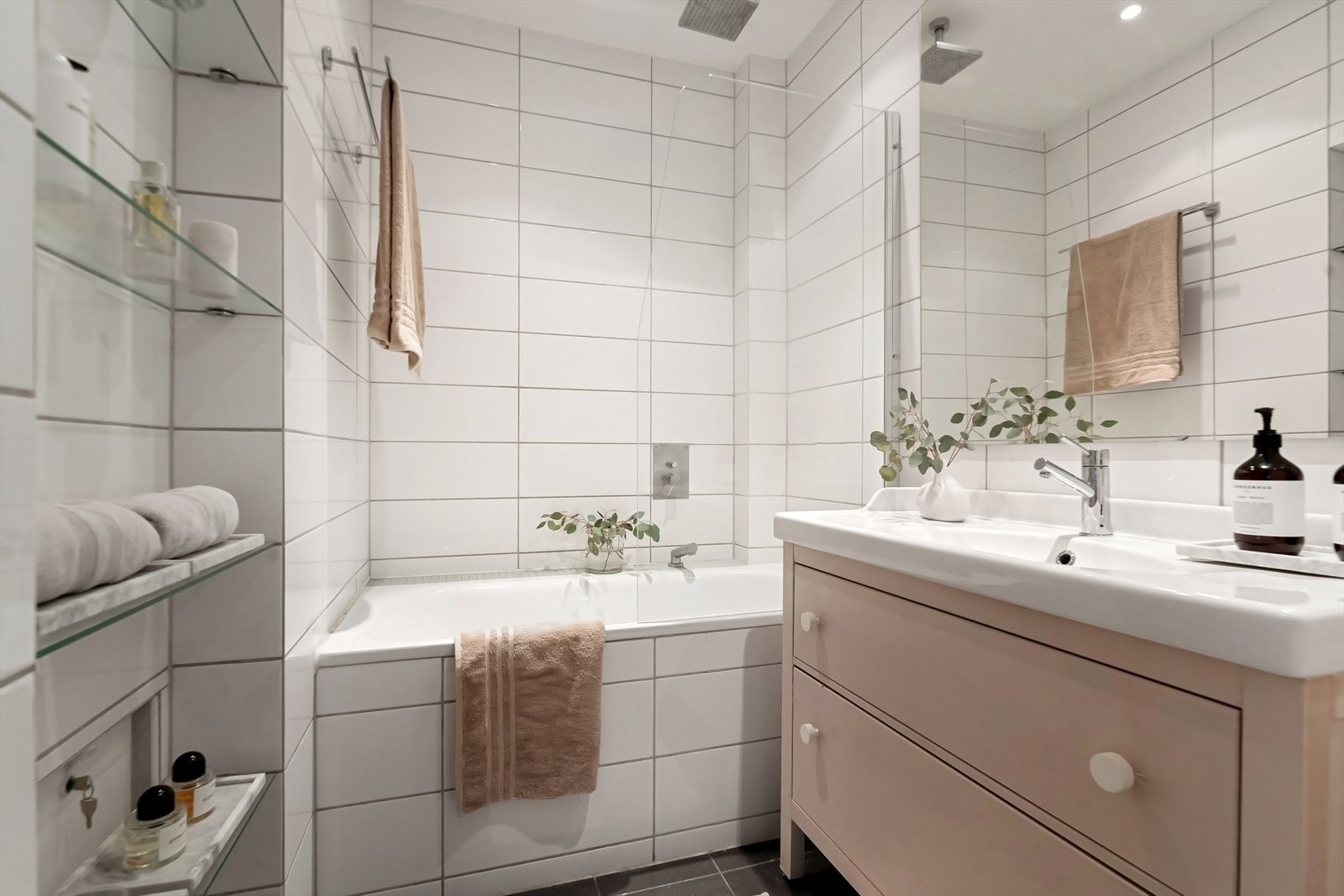 Baderommet er utstyrt med dusj i badekar, servant med innredning, speil over servant og klosett Galleribilde