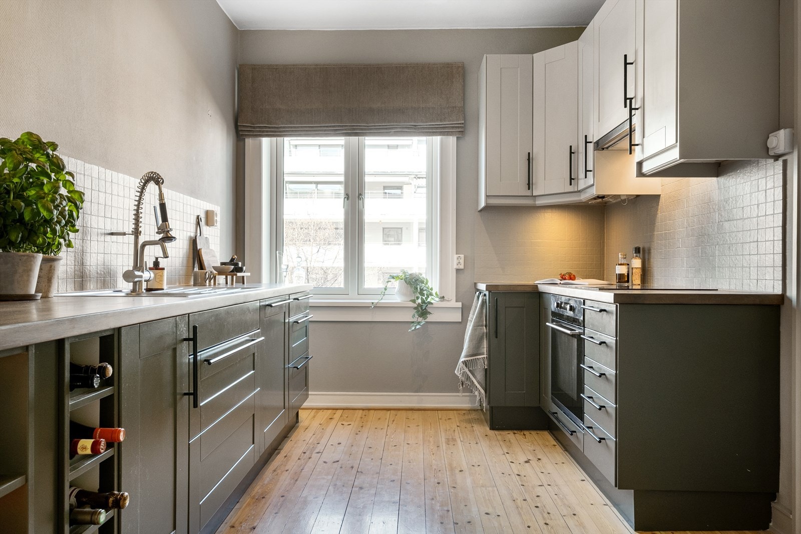 Kjøkkeninnredning med profilerte fronter, heltre benkeplate med nedfelt vaskekum og fliser over benkeplaten. Galleribilde