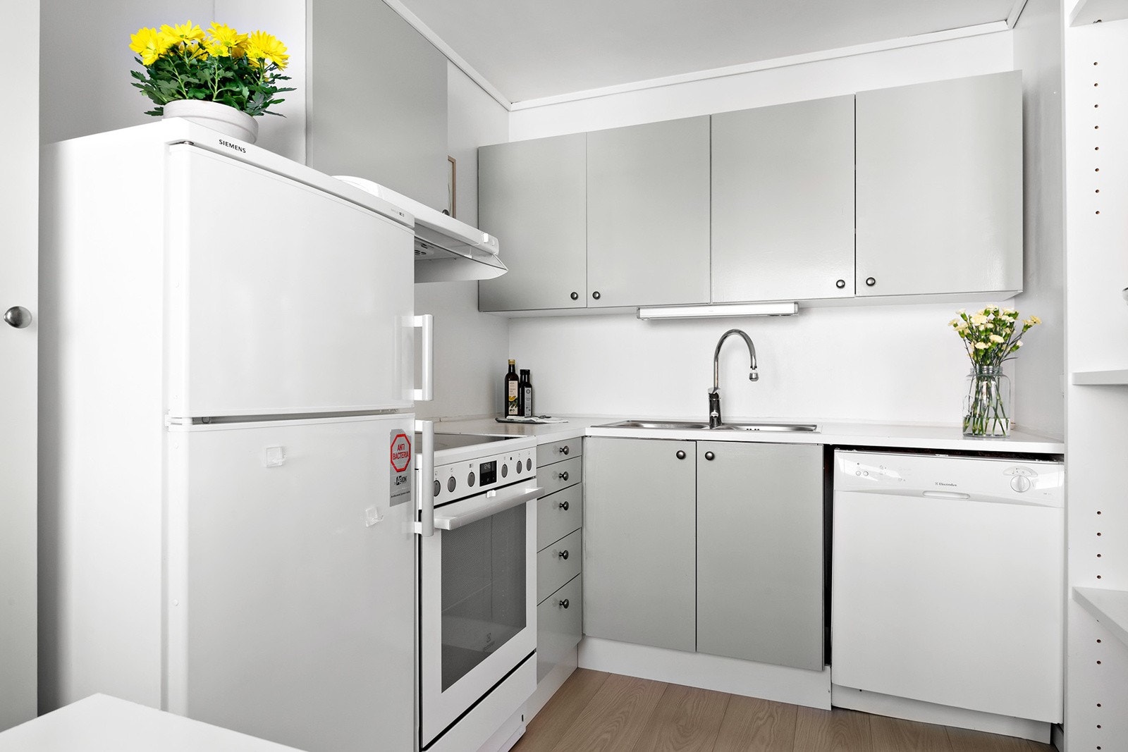 Kjøkkeninnredning med slette fronter og benkeplate av laminat. Nedsenket oppvaskkum av metall og ett-greps armatur. Benkeskapsbelysning under overskap samt frittstående hvitevarer som kjøleskap, komfyr og oppvaskmaskin. Galleribilde