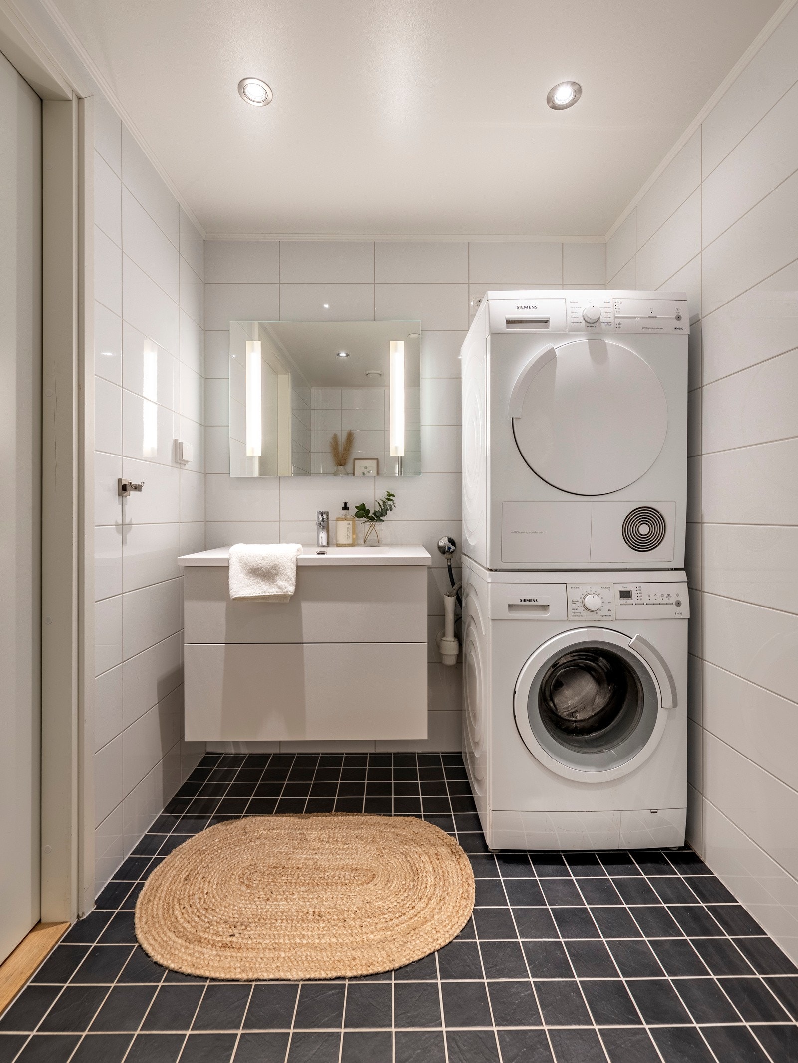 Badet byr på servantinnredning, speil på vegg over servant, vegghengt toalett og dusjhjørne med svingbare glassdører. Galleribilde