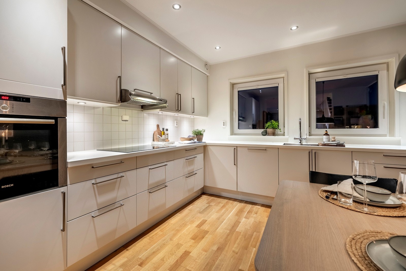 Kjøkkenet byr på integrerte hvitevarer som induksjonstopp, komfyr, oppvaskmaskin og kjøleskap med frysedel. Galleribilde