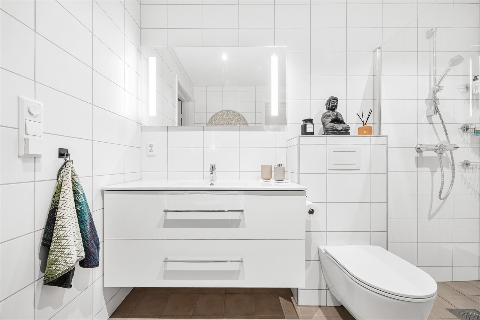 Badet har baderomsinnredning med lagringsplass, vegghengt toalett, og dusjsone med glassvegger. Galleribilde