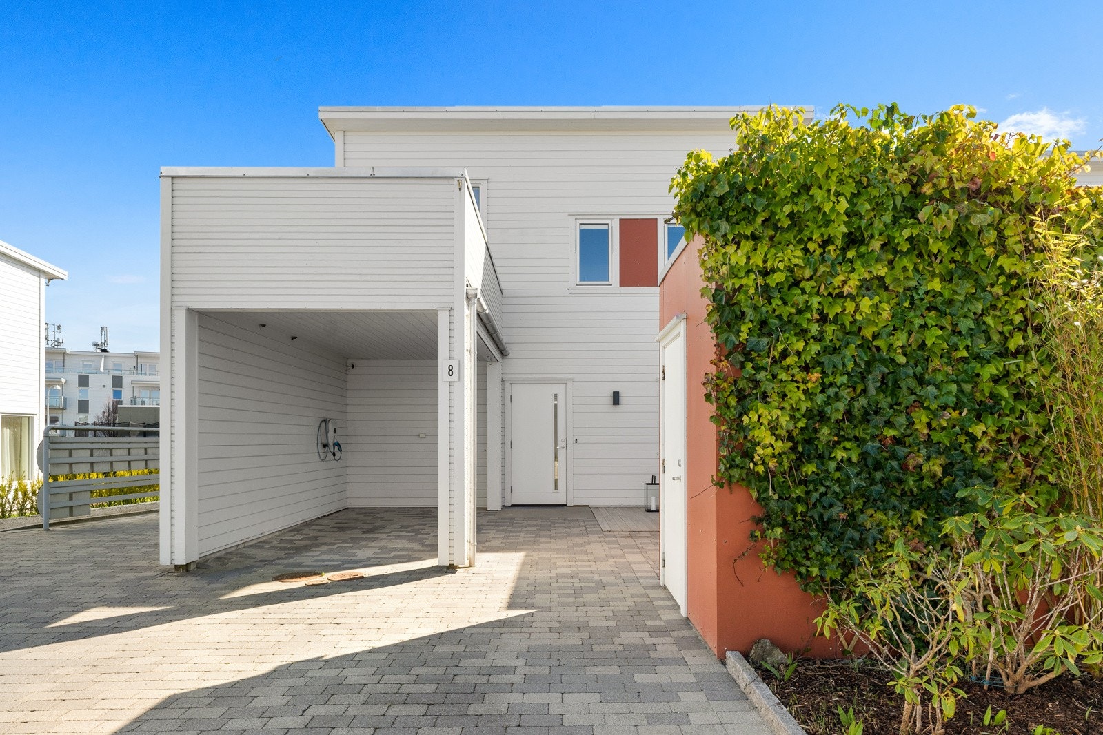 Bilen parkeres i carport som har elbil-lader eller i pent steinblagt gårdsrom. Galleribilde