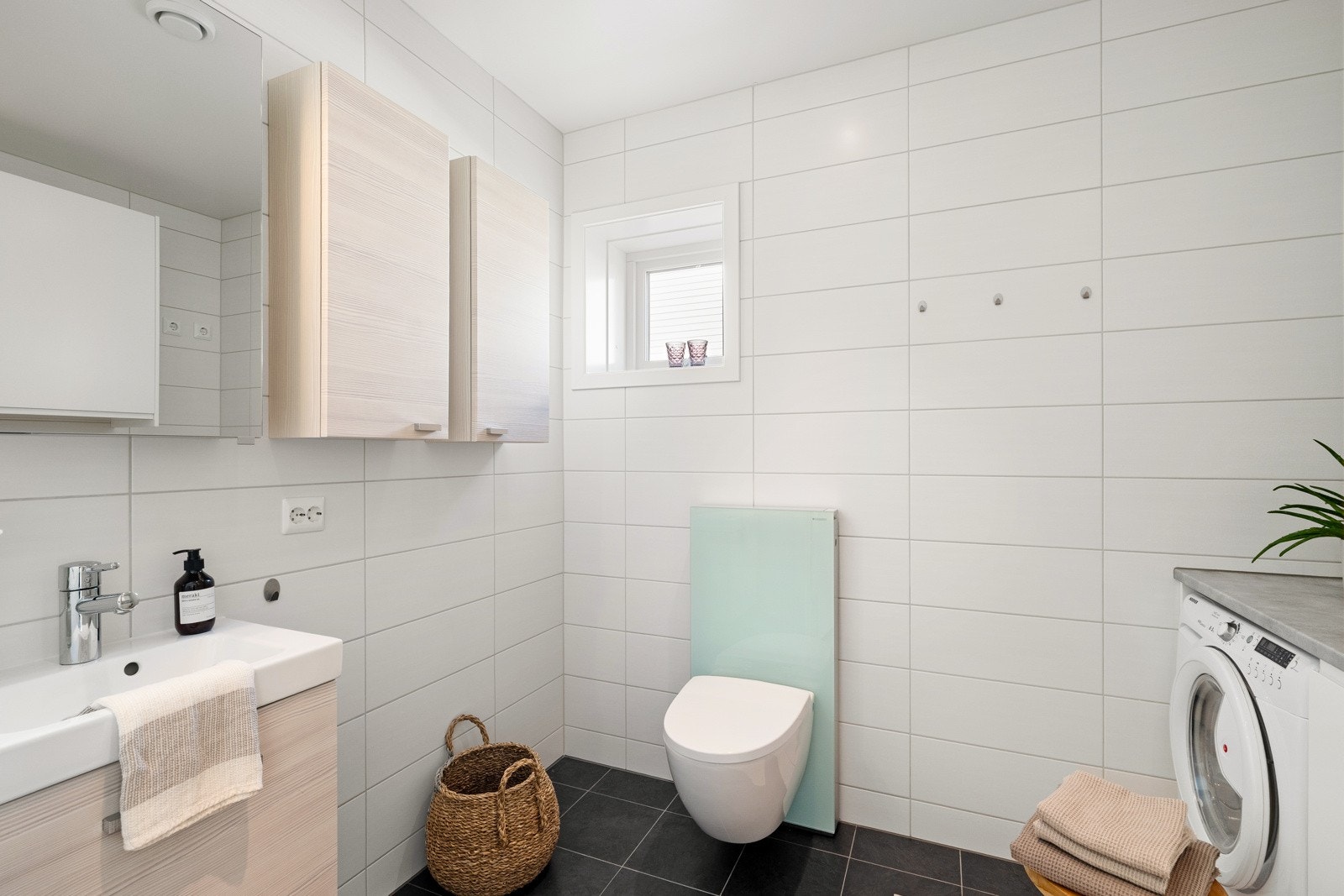 Badet er innredet med seksjon med servant, speil og vegghengt toalett med skjult sisterne. Galleribilde