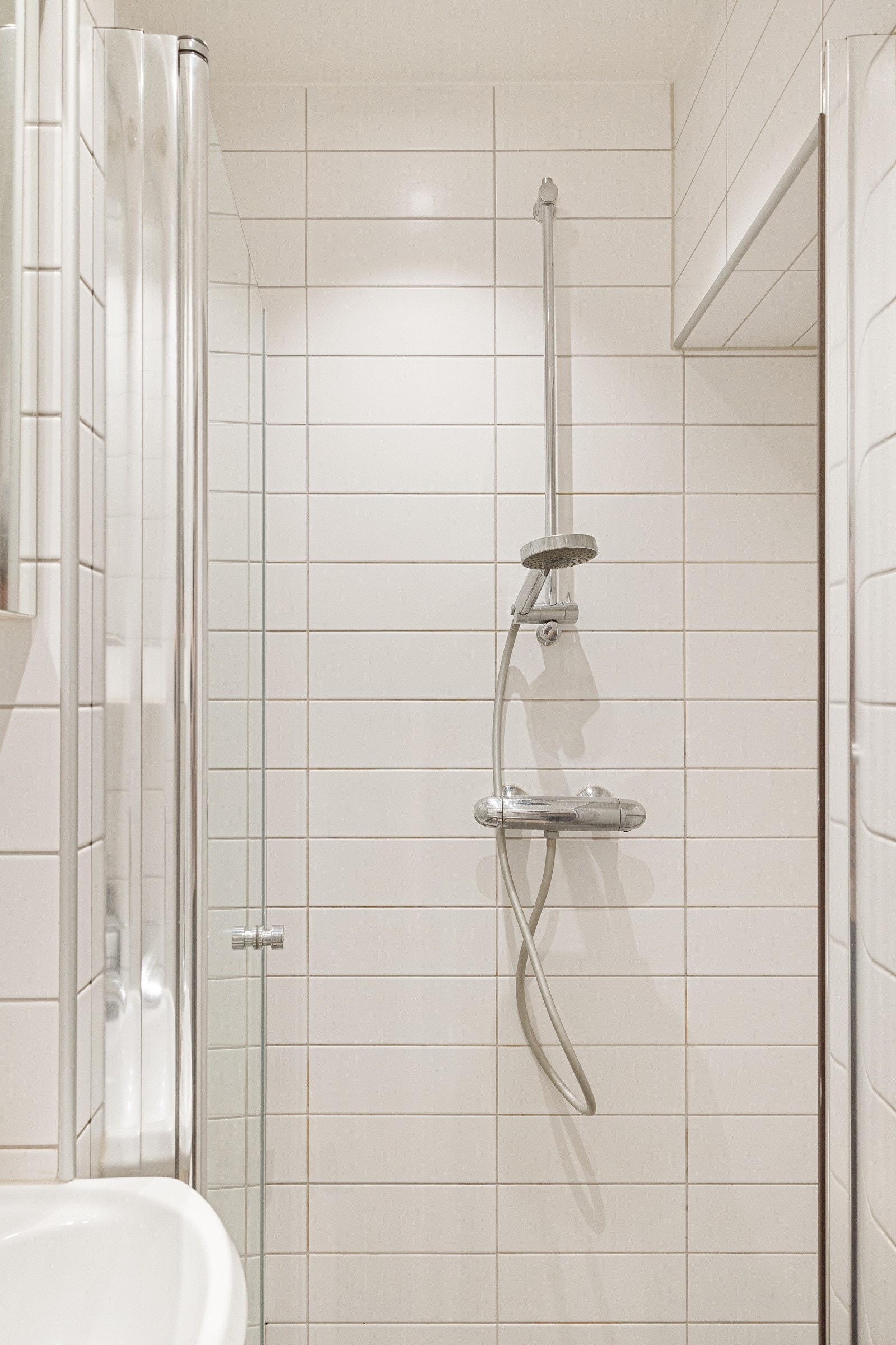 Innredningen byr på servantskap med glatte, folierte fronter og heldekkende servant. Speilskap og lysarmatur på vegg over servant, samt dusjhjørne og toalett. Galleribilde