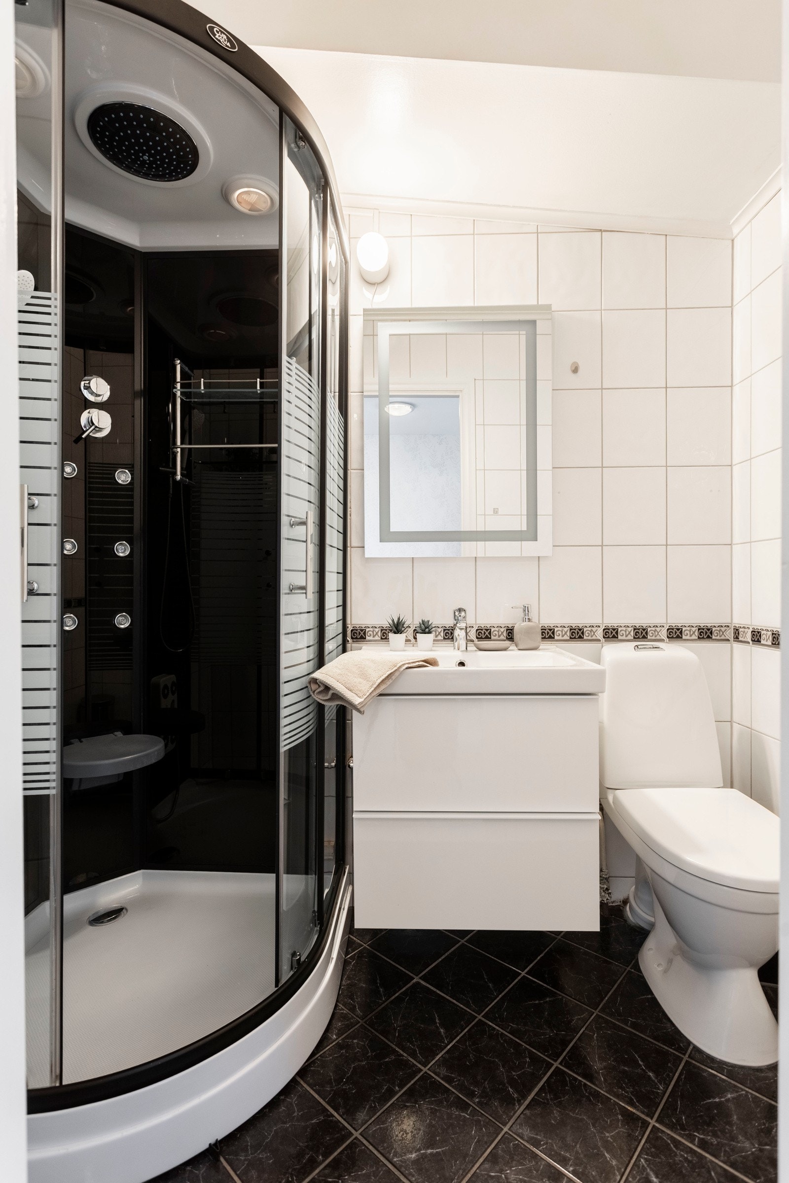 Badet er smart innredet for å utnytte arealet maksimalt. Med lyse fliser, moderne baderomsinnredning og praktisk dusjløsning føles rommet både funkjsonelt og innbydende. Galleribilde