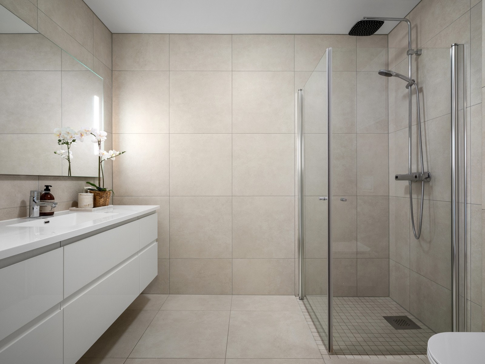 Lekkert flislagt bad med varme i gulvet og baderomsseksjon fra HTH Galleribilde