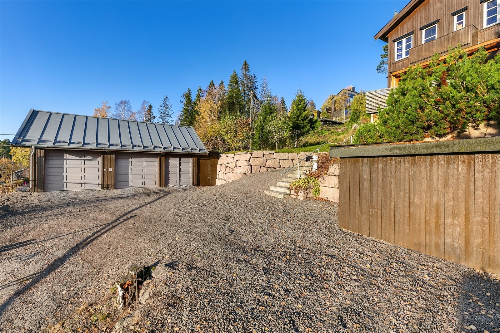 Fra hovedveien går det en liten stikkvei opp til en gruslagt gårdsplass med hengergarasje og gode muligheter for parkering. Galleribilde