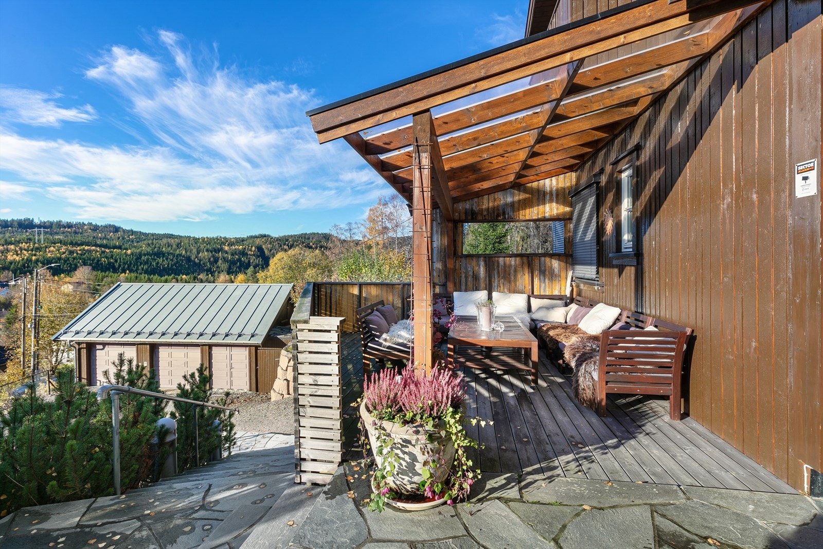 Ved inngangen ønskes man velkommen av en sydvestvendt terrasse med både skifer og trebord på dekket. Terrassen er delvis overbygd og har et areal på ca. 17 kvm. Galleribilde