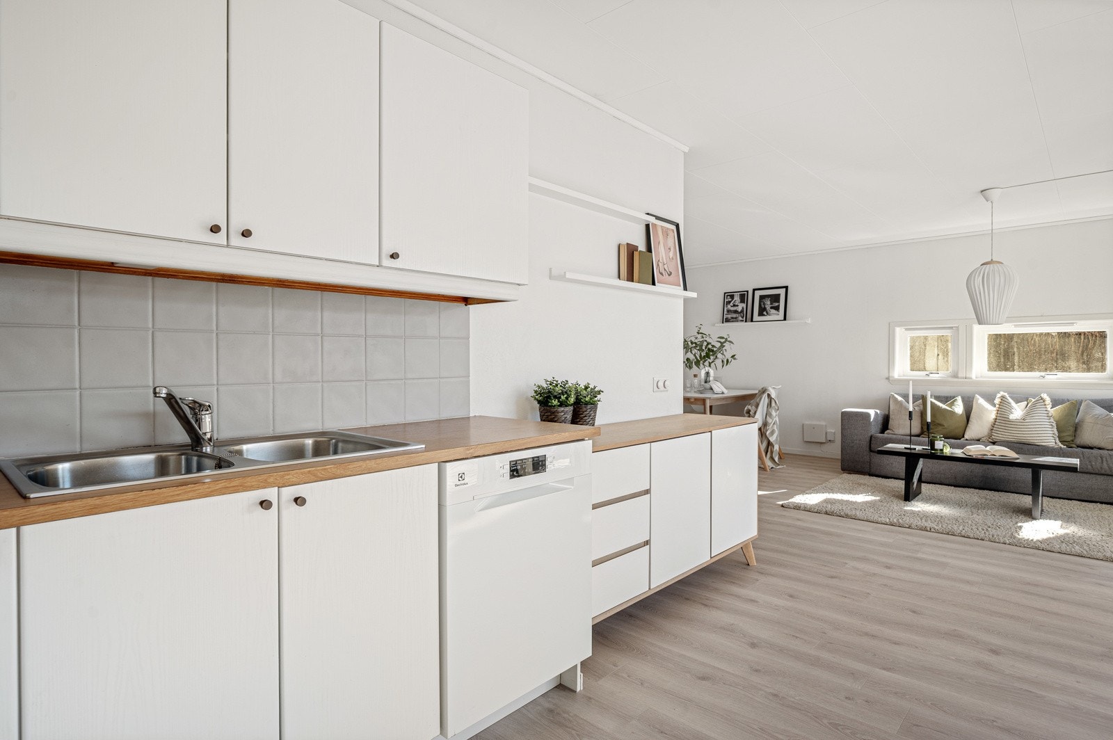 Benkeplate av laminat, oppvaskmaskin under kjøkkenbenk, frittstående komfyr og kjøleskap med fryser. Galleribilde