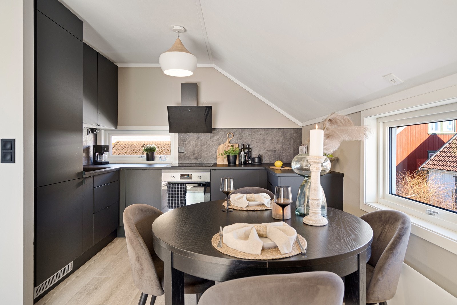 Kjøkkenet har takhøye skap, god arbeidsflyt, grå plater som backsplash og et nyere vindu over benken. Stekeovn, induksjonstopp, kjøl/fryseskap og oppvaskmaskin er integrert, og det er en ventilator med sort glassfront over kokesonen. Galleribilde