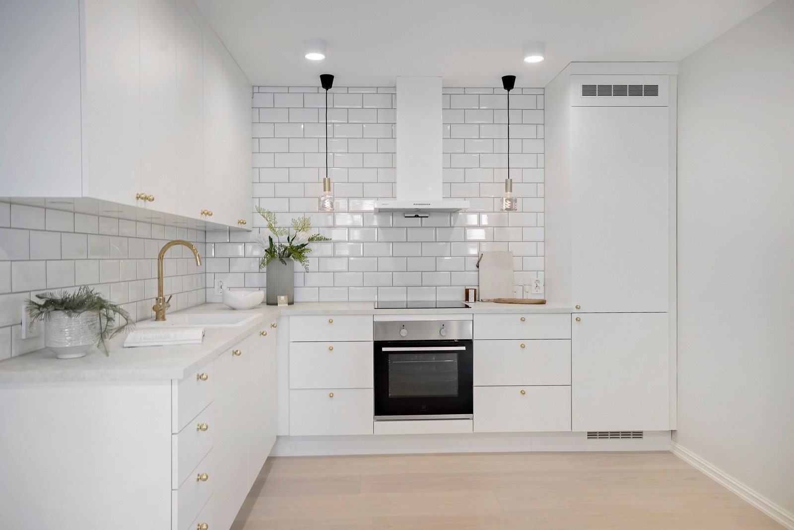 Kjøkkenet har en lys innredning med integrerte hvitevarer, messingdetaljer og klassiske metrofliser fra benk til tak. Galleribilde