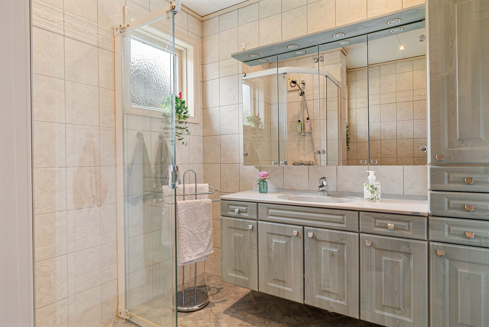 Badet er innredet med en romslig servant med både over- og underskap, samt et sideskap som gir godt med oppbevaringsplass. Galleribilde