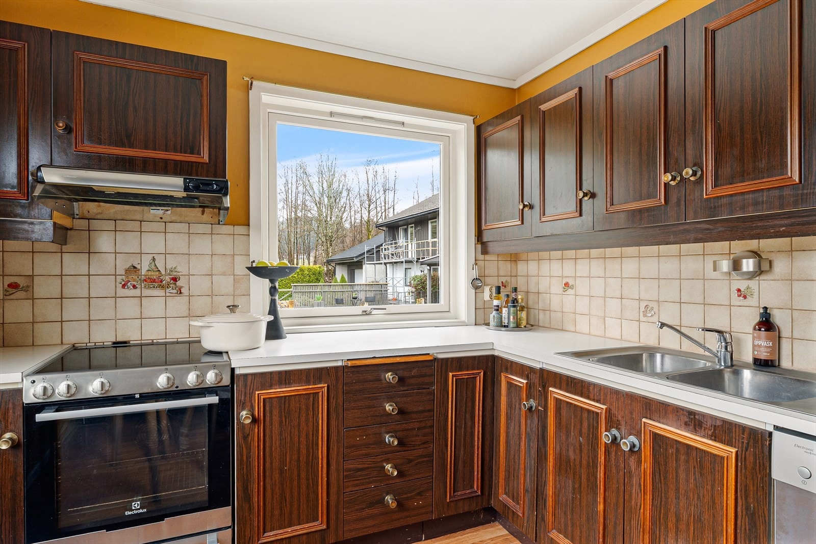 Kjøkkeninnredningen har profilerte fronter, og det er fliser på veggen over den laminatbelagte benkeplaten. Galleribilde