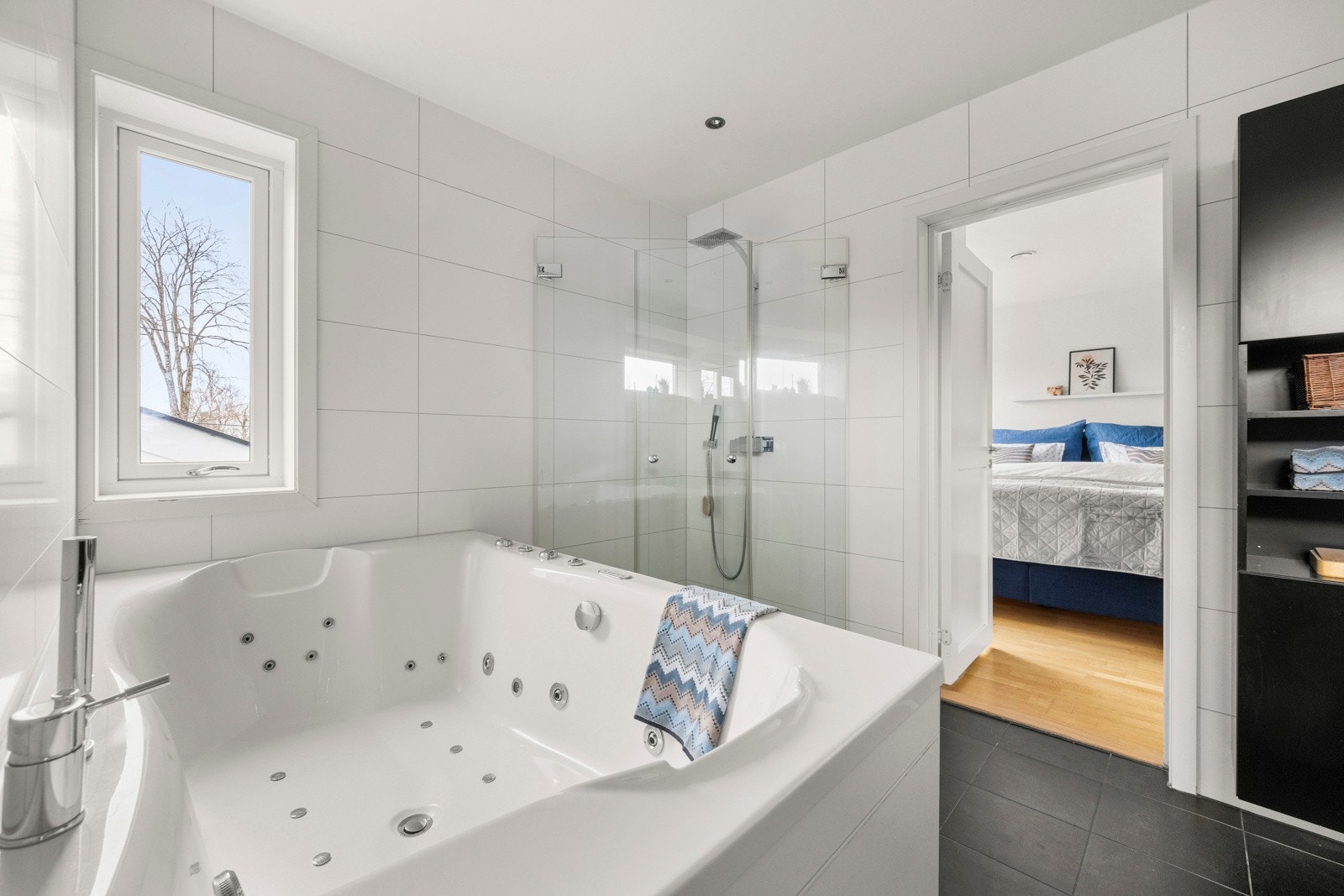 Hovedbadet i 2. etasje er eksklusivt utstyrt med et innmurt dobbelt massasje-/boblekar, et romslig dusjhjørne (1m x 1m) med vegghengte glassdører, samt en nedsenket dusjsone med mosaikkfliser. Galleribilde