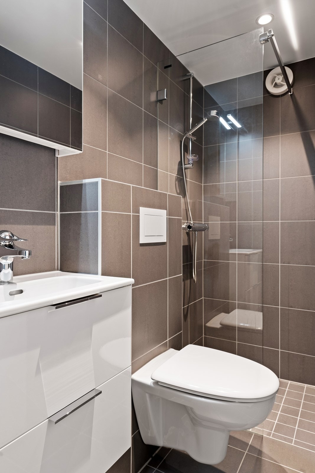Flislagt bad i kjeller med dusj, servantinnredning og wc. Alt nytt. Galleribilde