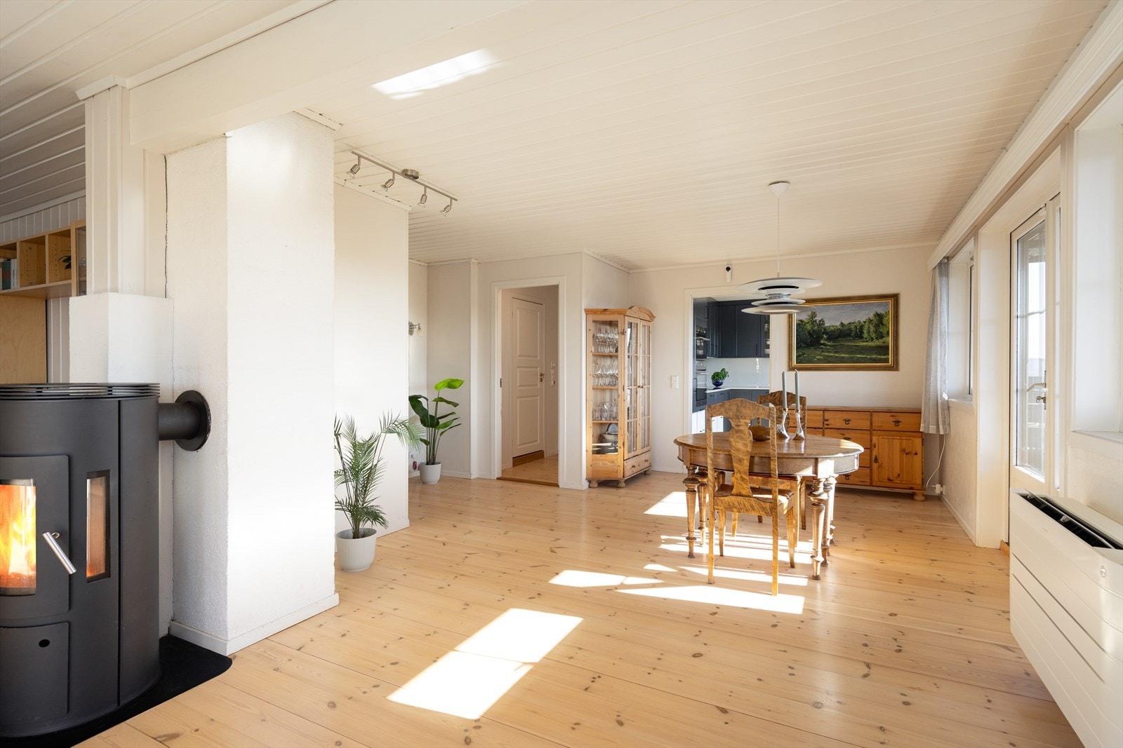 Romslig stue med vedovn med glass på tre sider hvor det er fint innsyn til flammene Galleribilde