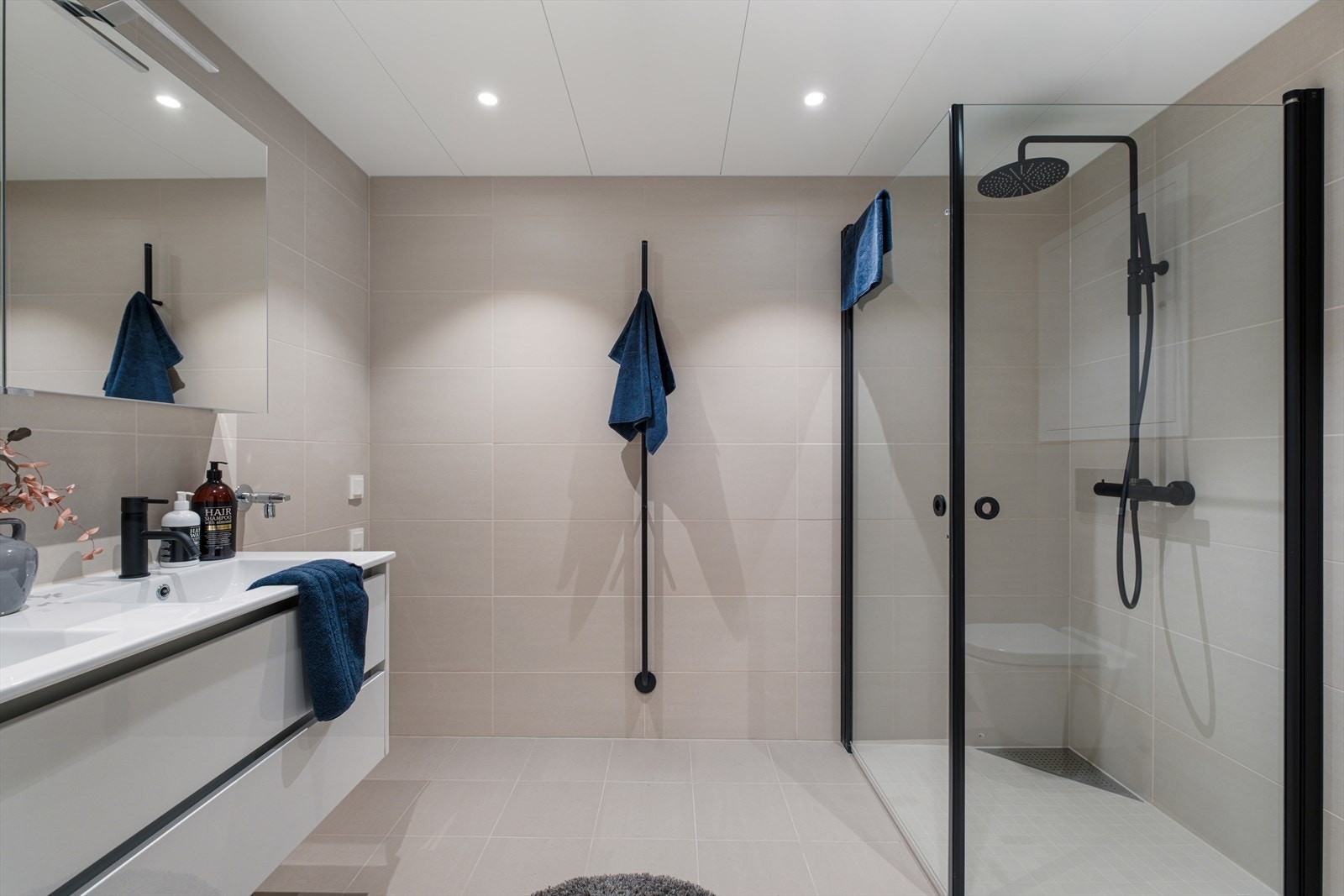 Badet er påkostet med blant annet tilvalgene Tappwell servantbatteri, dusjarmatur, dusjhjørne, håndklevarmer, toalettrullholder i gjennomgående matt sort Galleribilde