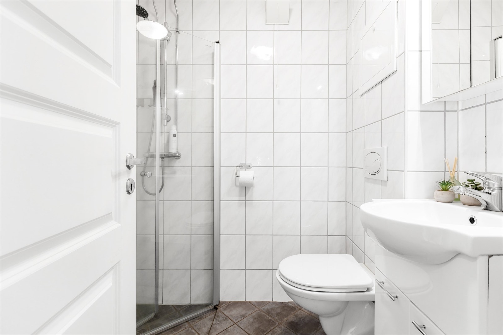 Badet har dusjhjørne med foldedører av glass Galleribilde