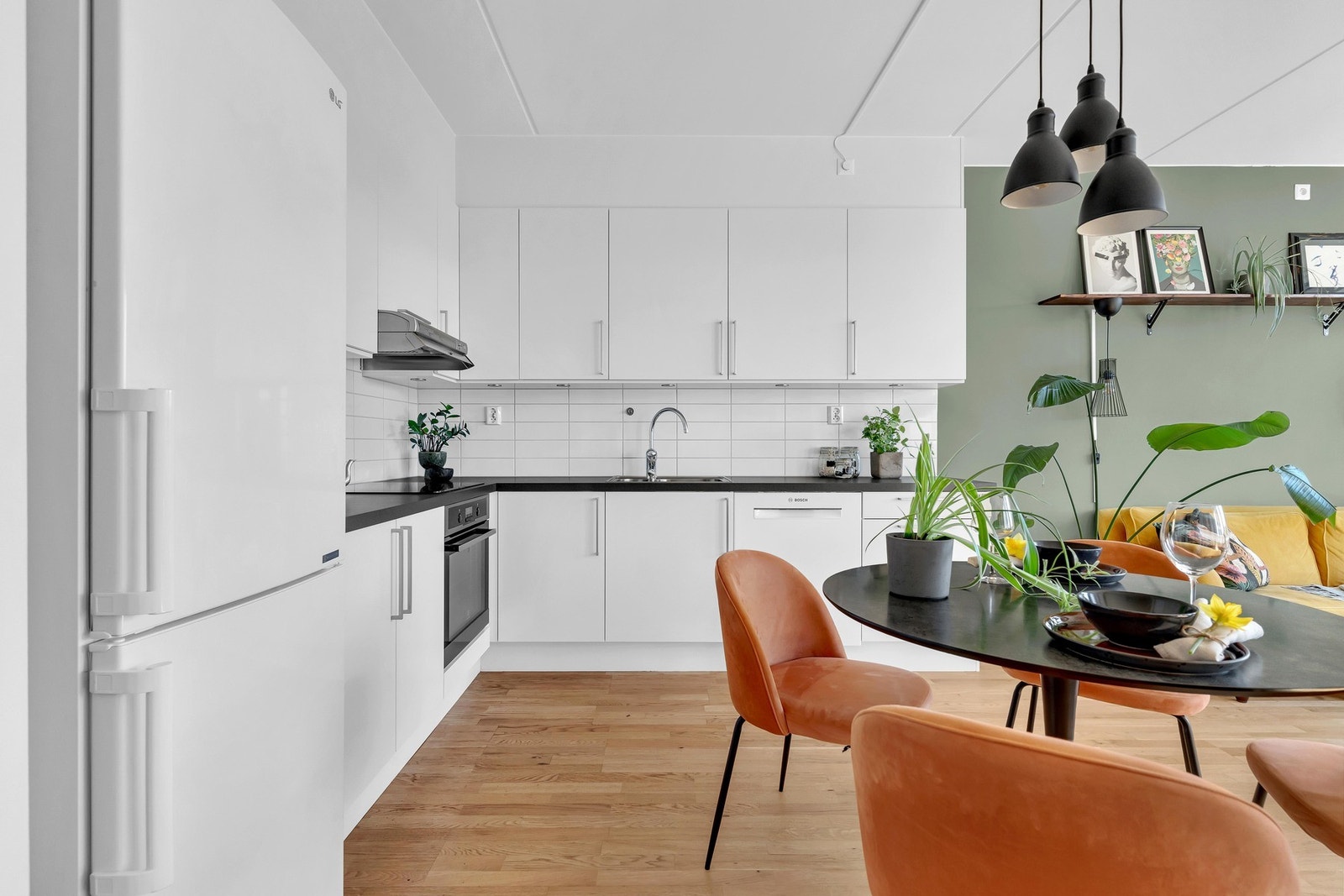 Integrert komfyr med nedfelt induksjonstopp og forøvrig frittstående hvitevarer på kjøkkenet. Galleribilde