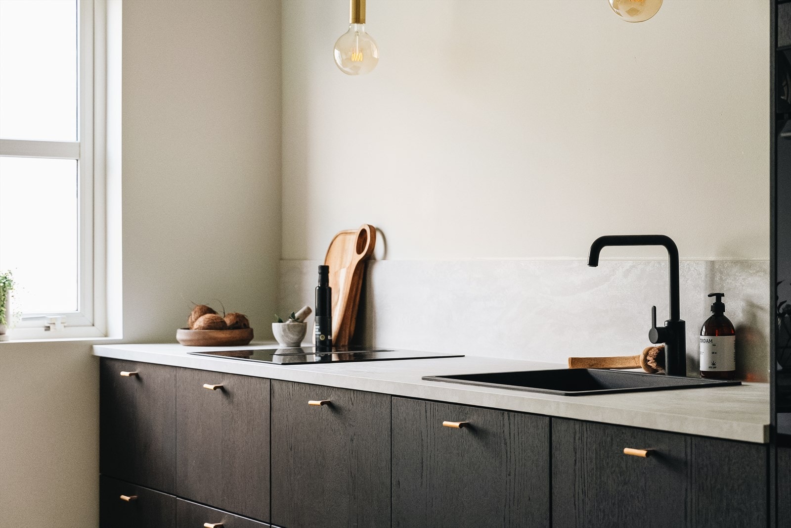 Gjennomførte detaljer med blant annet lamper over kjøkkenbenk som står i stil med håndtakene Galleribilde