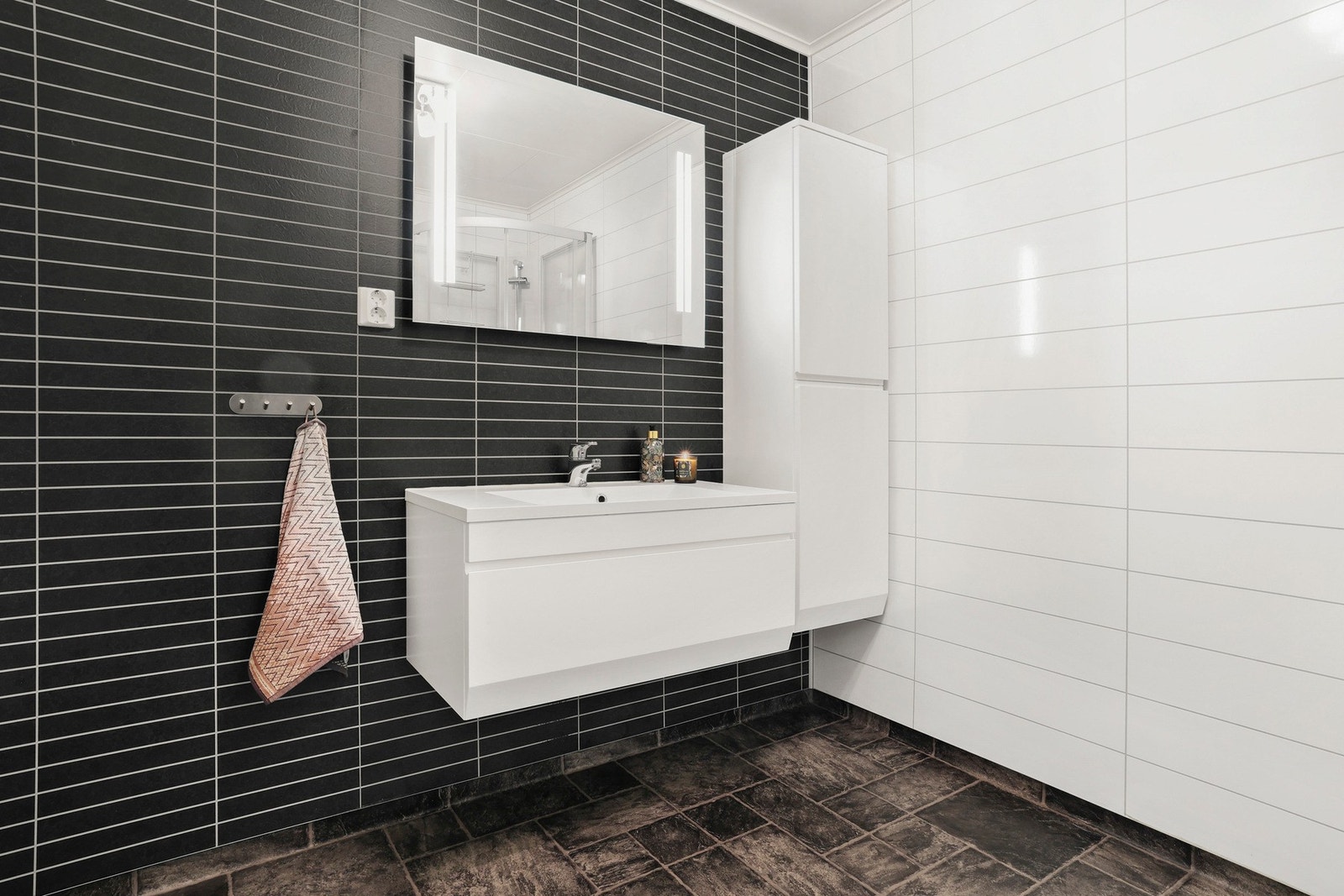 Det er vegghengt servantinnredning med speil og lys. Galleribilde